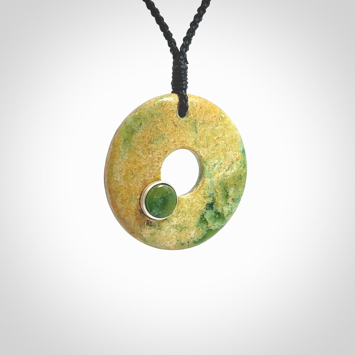 Hand carved New Zealand flower Jade disc drop pendant with smaller pounamu and silver insert. Made by Ana Krakosky for NZ Pacific in New Zealand Pounamu, jade. A beautiful orange and green jade disc necklace with black adjustable cord.