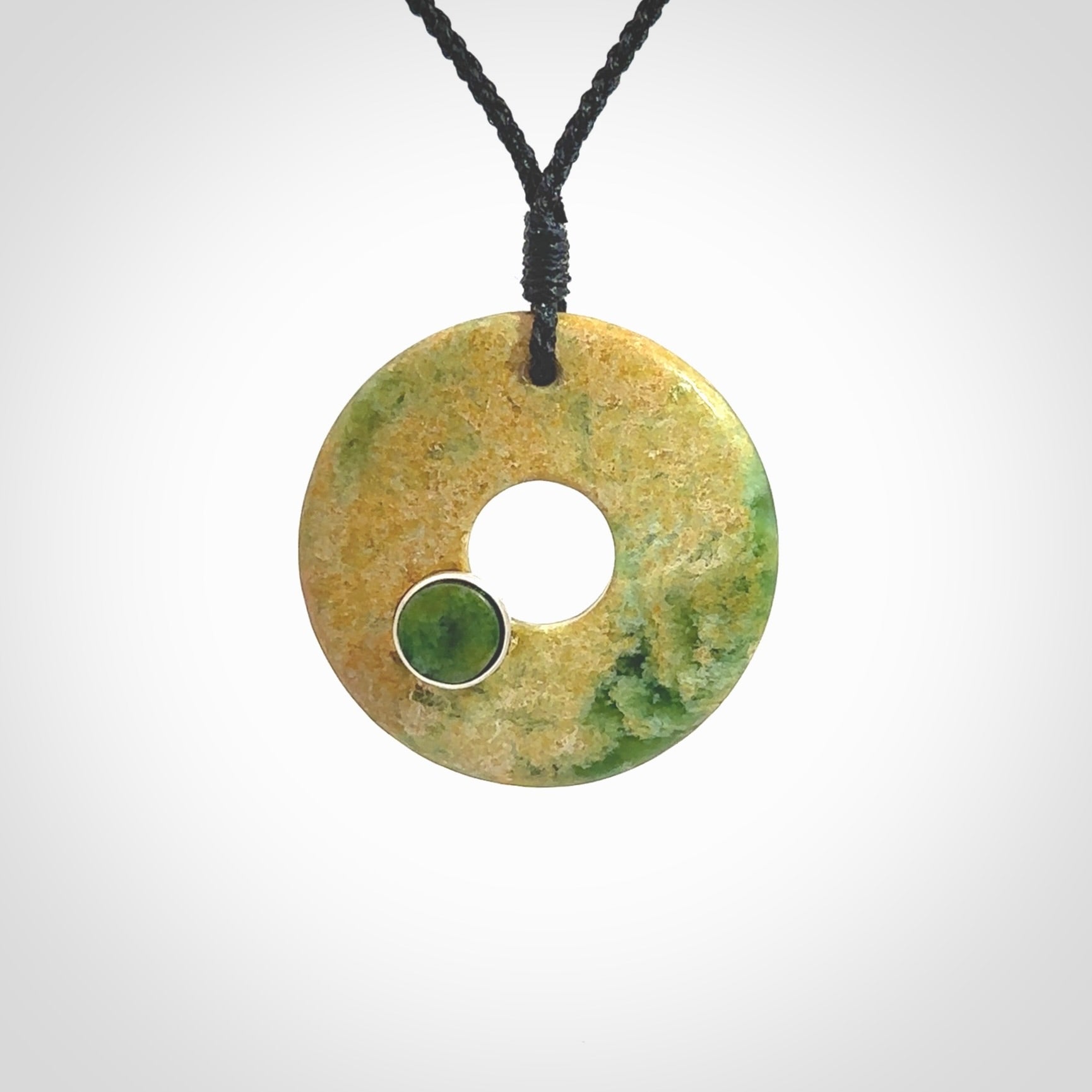 Hand carved New Zealand flower Jade disc drop pendant with smaller pounamu and silver insert. Made by Ana Krakosky for NZ Pacific in New Zealand Pounamu, jade. A beautiful orange and green jade disc necklace with black adjustable cord.