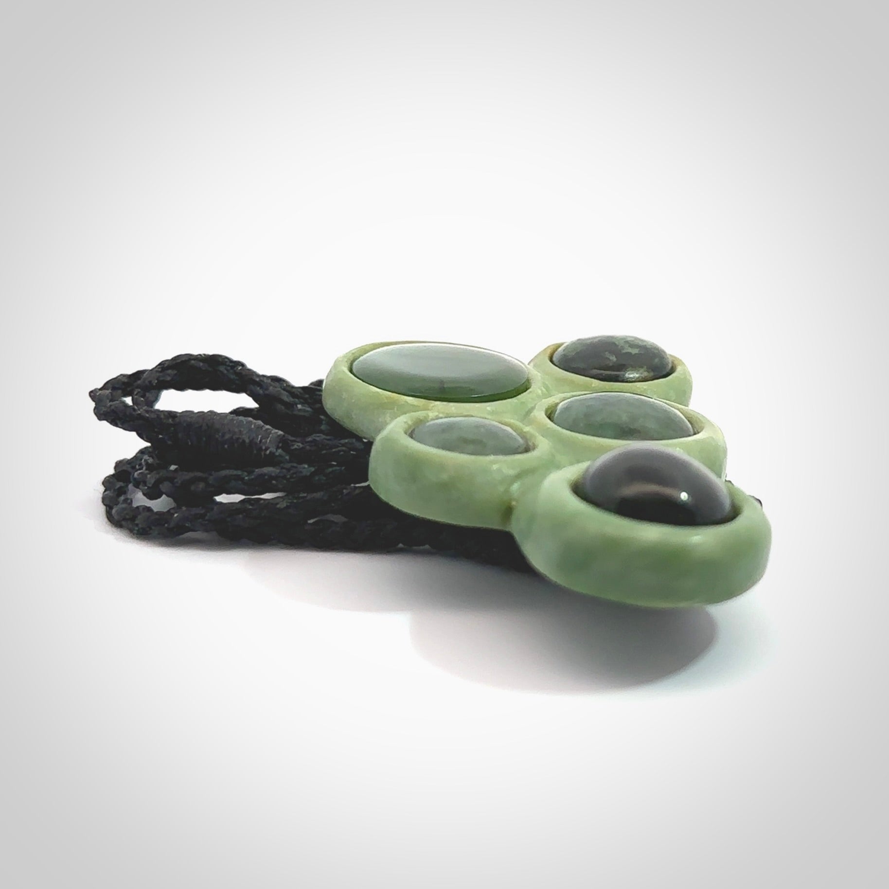 Hand carved New Zealand Jade bubbles drop pendant. Made by Ana Krakosky for NZ Pacific in New Zealand Pounamu, jade. A beautiful light and dark green jade drop of bubbles necklace with black adjustable cord.