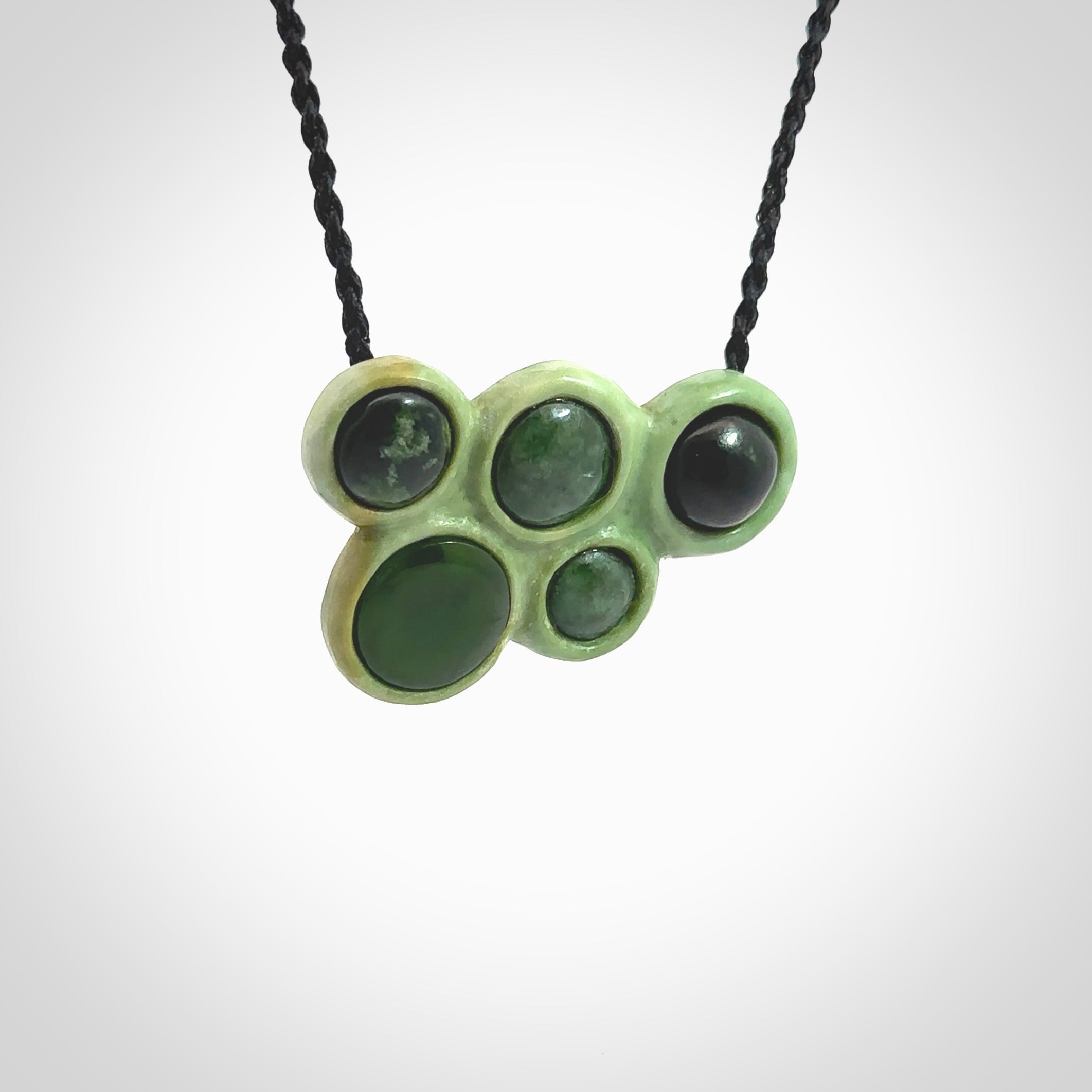 Hand carved New Zealand Jade bubbles drop pendant. Made by Ana Krakosky for NZ Pacific in New Zealand Pounamu, jade. A beautiful light and dark green jade drop of bubbles necklace with black adjustable cord.