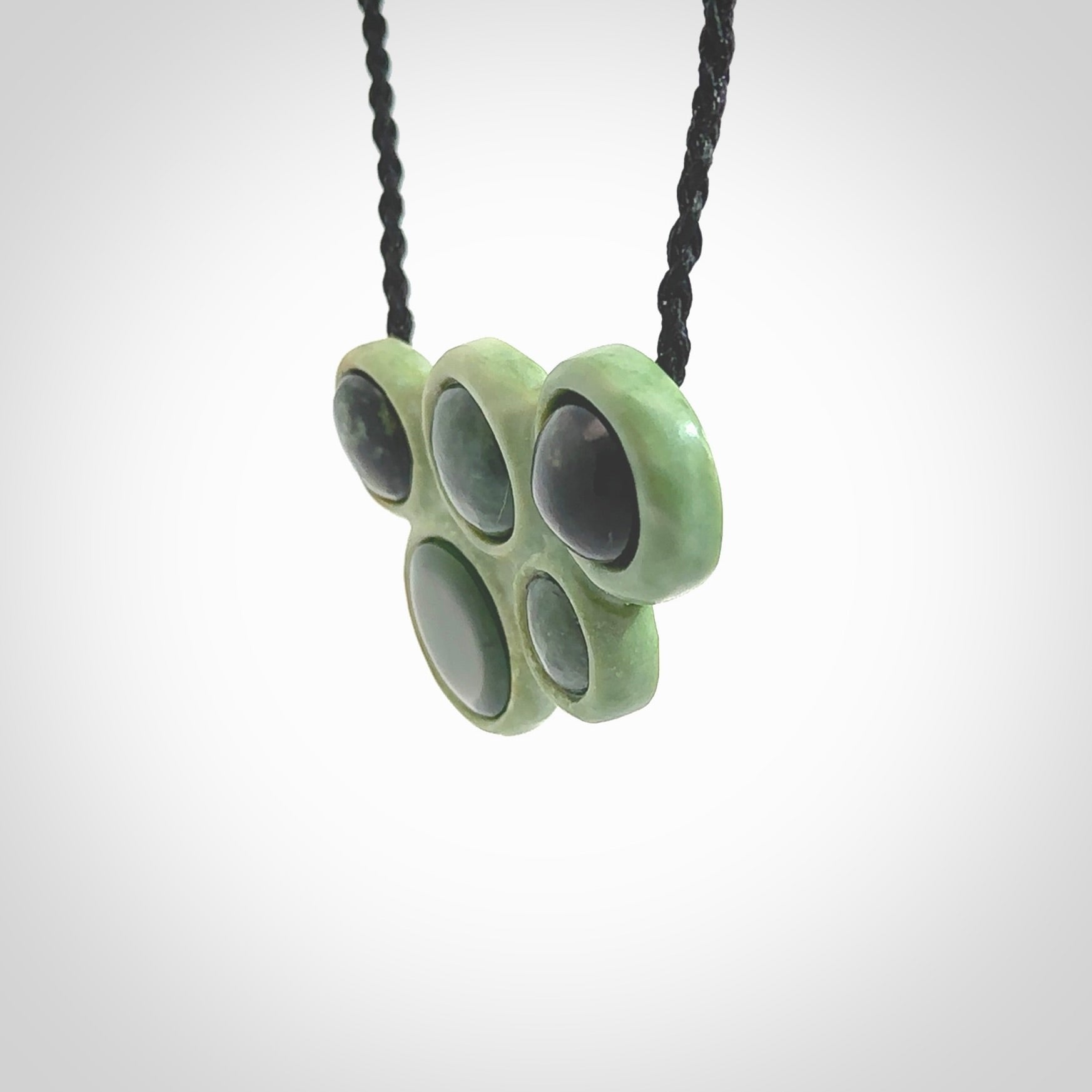 Hand carved New Zealand Jade bubbles drop pendant. Made by Ana Krakosky for NZ Pacific in New Zealand Pounamu, jade. A beautiful light and dark green jade drop of bubbles necklace with black adjustable cord.