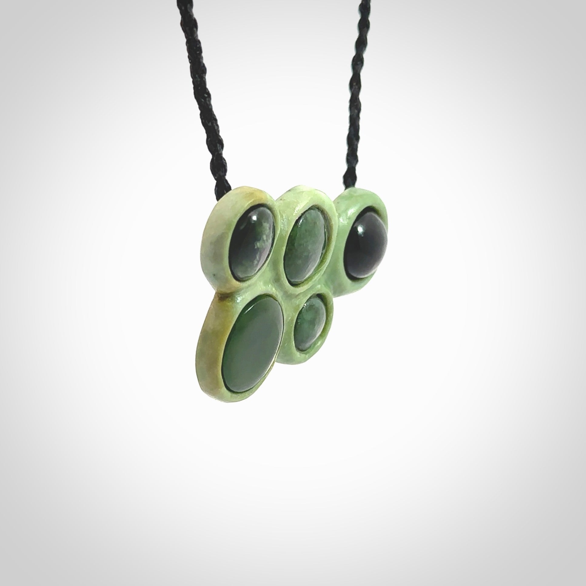 Hand carved New Zealand Jade bubbles drop pendant. Made by Ana Krakosky for NZ Pacific in New Zealand Pounamu, jade. A beautiful light and dark green jade drop of bubbles necklace with black adjustable cord.