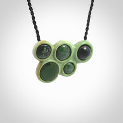 Hand carved New Zealand Jade bubbles drop pendant. Made by Ana Krakosky for NZ Pacific in New Zealand Pounamu, jade. A beautiful light and dark green jade drop of bubbles necklace with black adjustable cord.