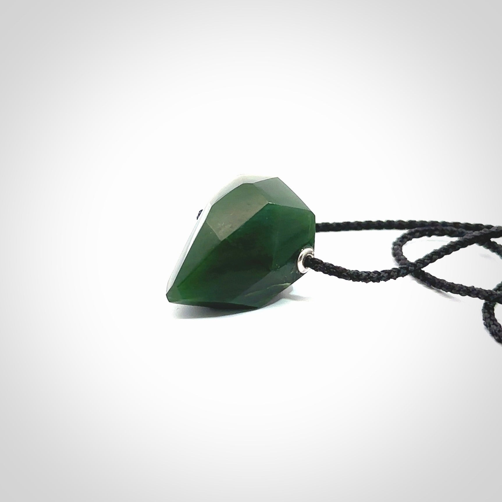 Hand carved New Zealand Jade facet drop pendant. Made by Ana Krakosky for NZ Pacific in New Zealand Pounamu, jade. A beautiful green marsden jade facet drop necklace with black adjustable cord.