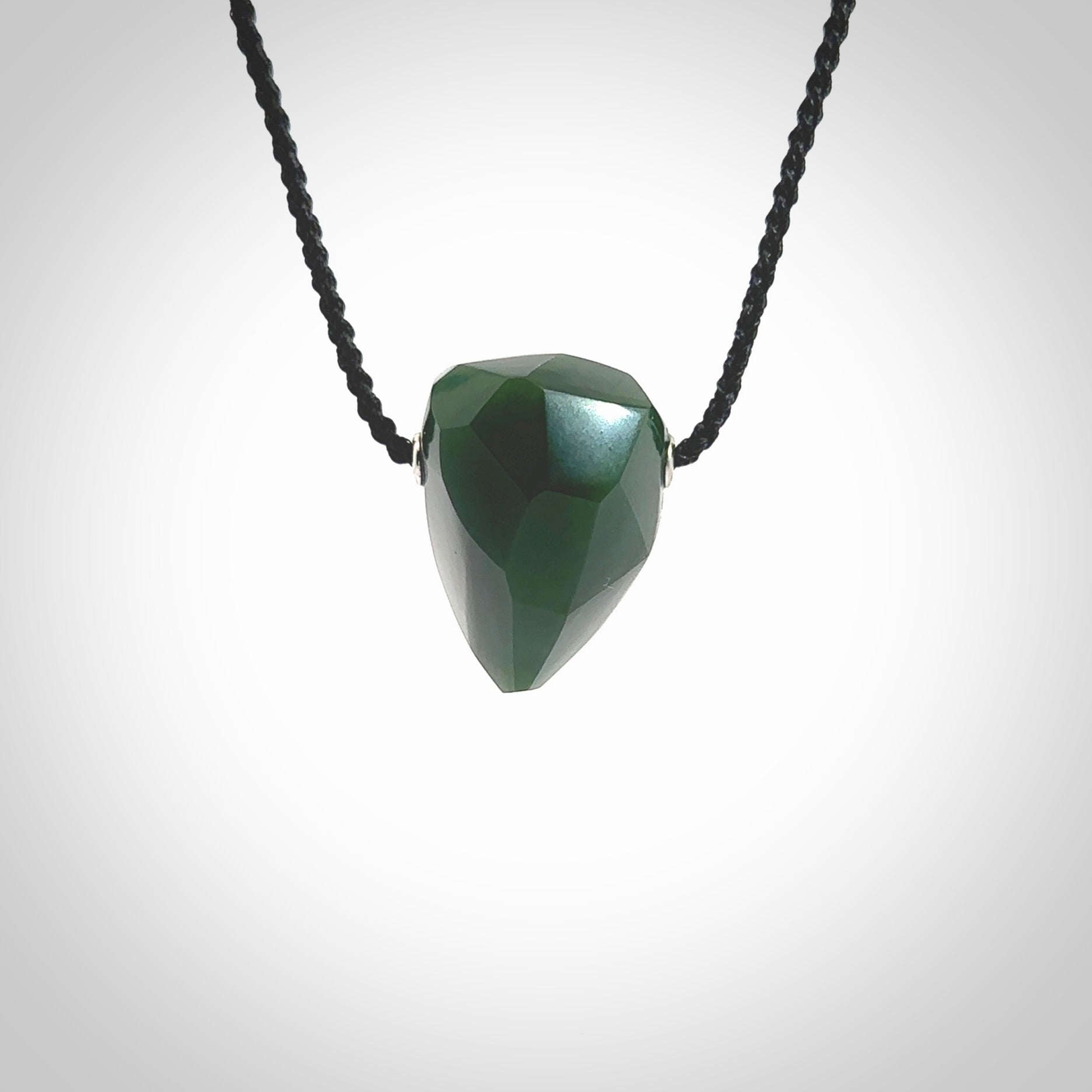 Hand carved New Zealand Jade facet drop pendant. Made by Ana Krakosky for NZ Pacific in New Zealand Pounamu, jade. A beautiful green marsden jade facet drop necklace with black adjustable cord.