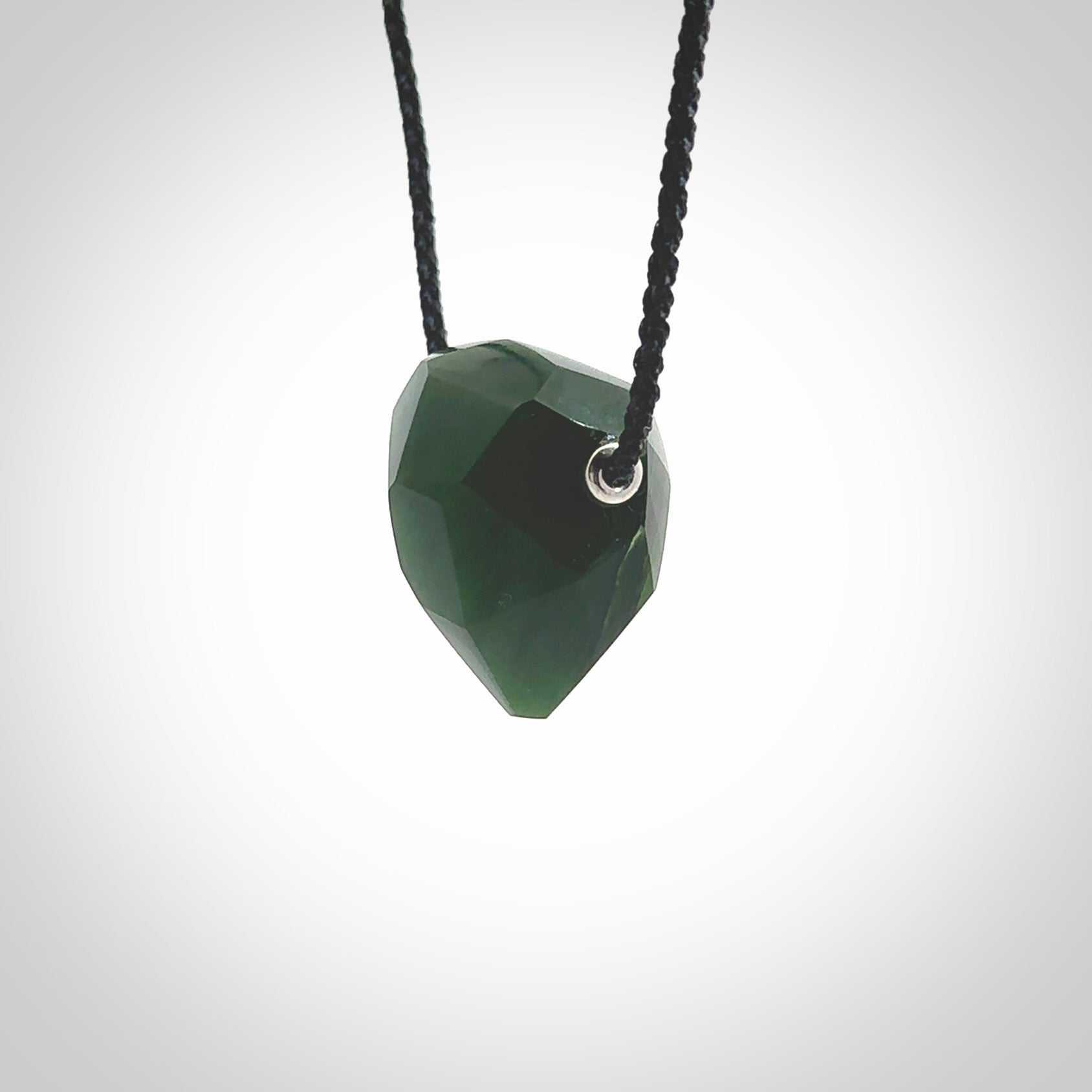 Hand carved New Zealand Jade facet drop pendant. Made by Ana Krakosky for NZ Pacific in New Zealand Pounamu, jade. A beautiful green marsden jade facet drop necklace with black adjustable cord.