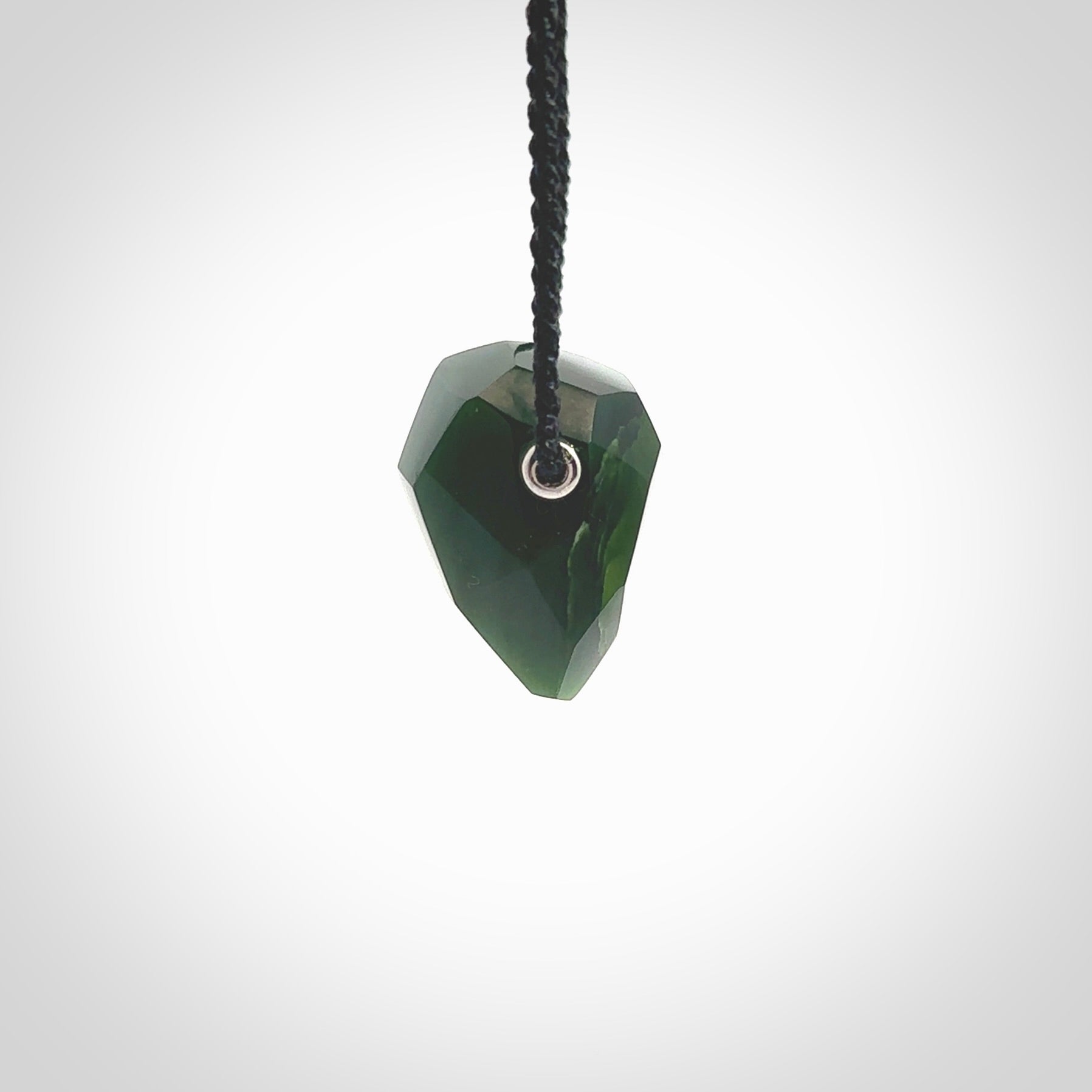 Hand carved New Zealand Jade facet drop pendant. Made by Ana Krakosky for NZ Pacific in New Zealand Pounamu, jade. A beautiful green marsden jade facet drop necklace with black adjustable cord.