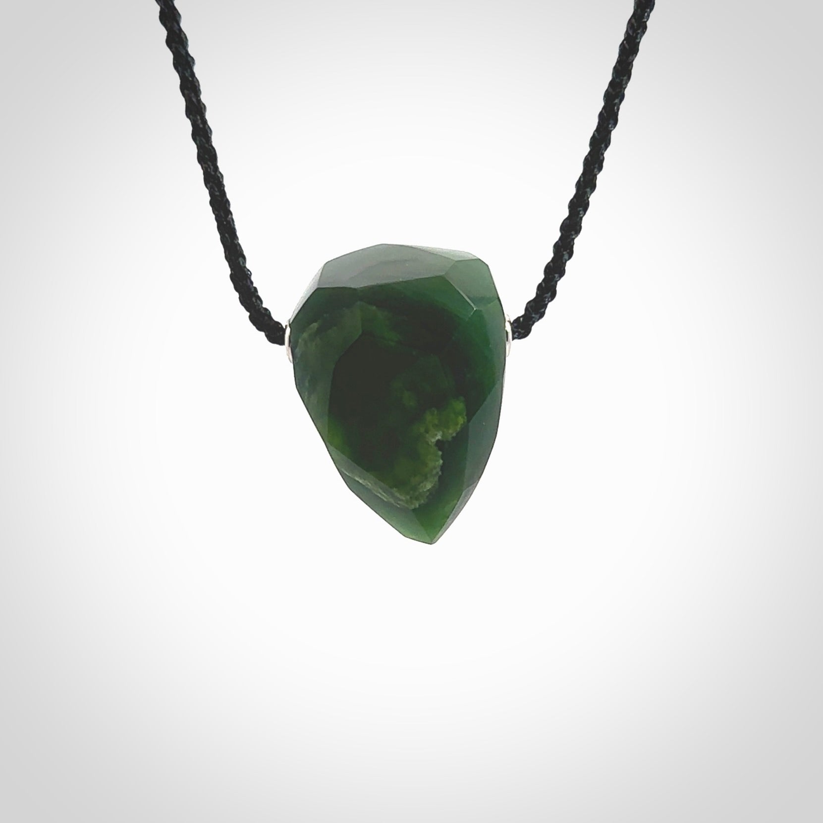 Hand carved New Zealand Jade facet drop pendant. Made by Ana Krakosky for NZ Pacific in New Zealand Pounamu, jade. A beautiful green marsden jade facet drop necklace with black adjustable cord.