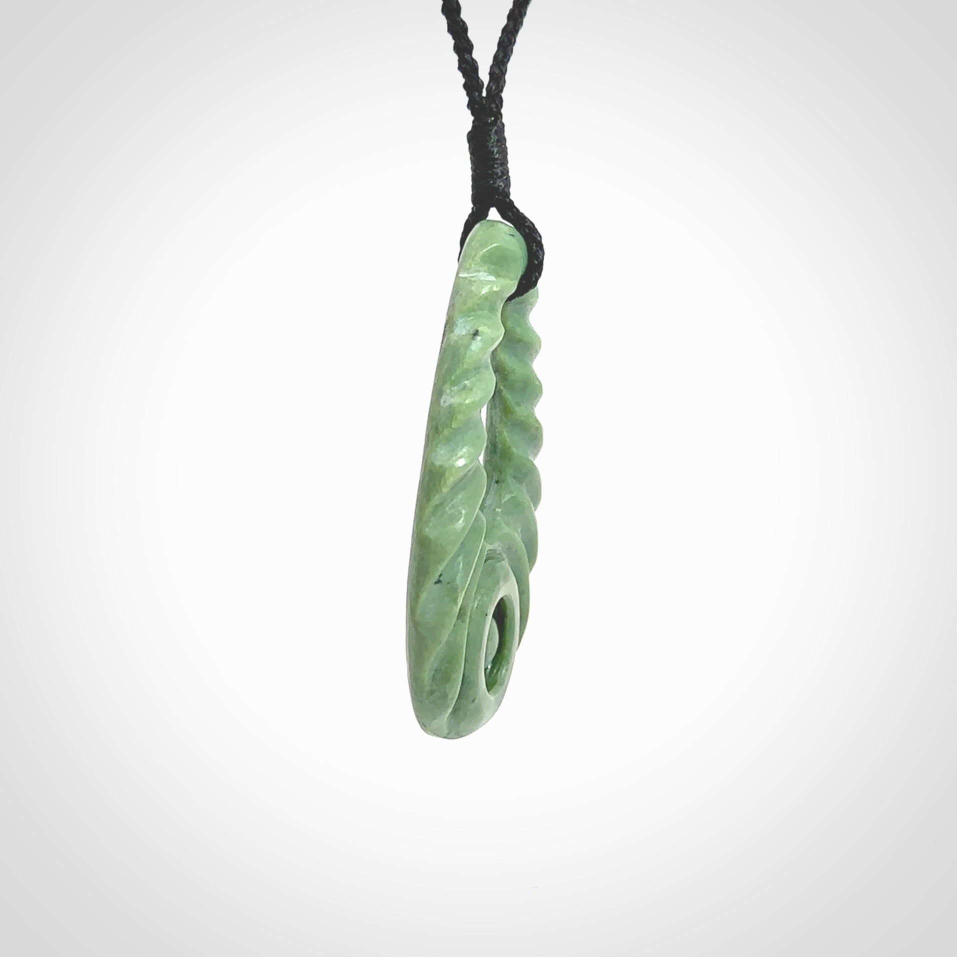 Hand carved New Zealand Jade ripples drop pendant. Made by Ana Krakosky for NZ Pacific in New Zealand Pounamu, jade. A beautiful light green jade ripples drop necklace with black adjustable cord.