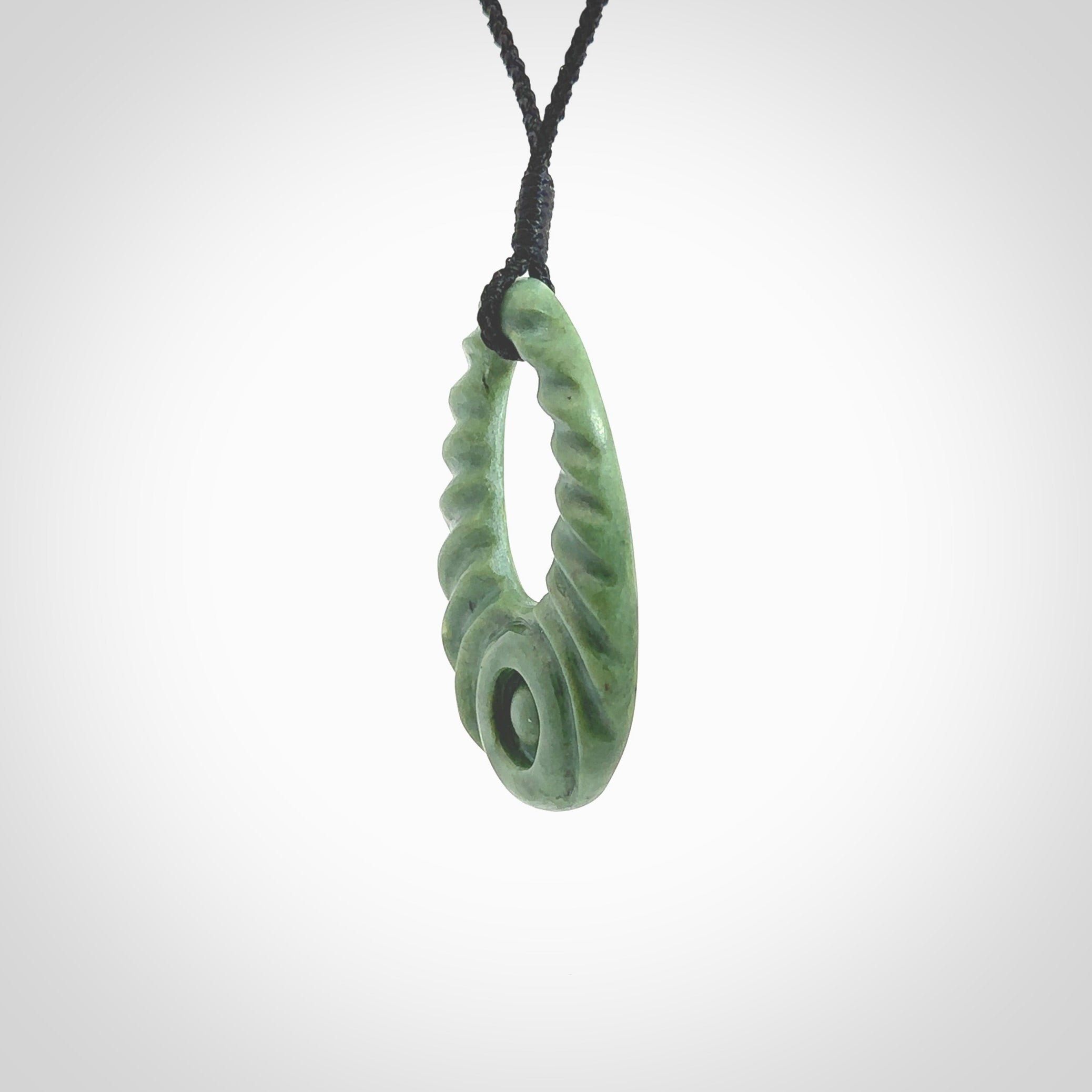 Hand carved New Zealand Jade ripples drop pendant. Made by Ana Krakosky for NZ Pacific in New Zealand Pounamu, jade. A beautiful light green jade ripples drop necklace with black adjustable cord.