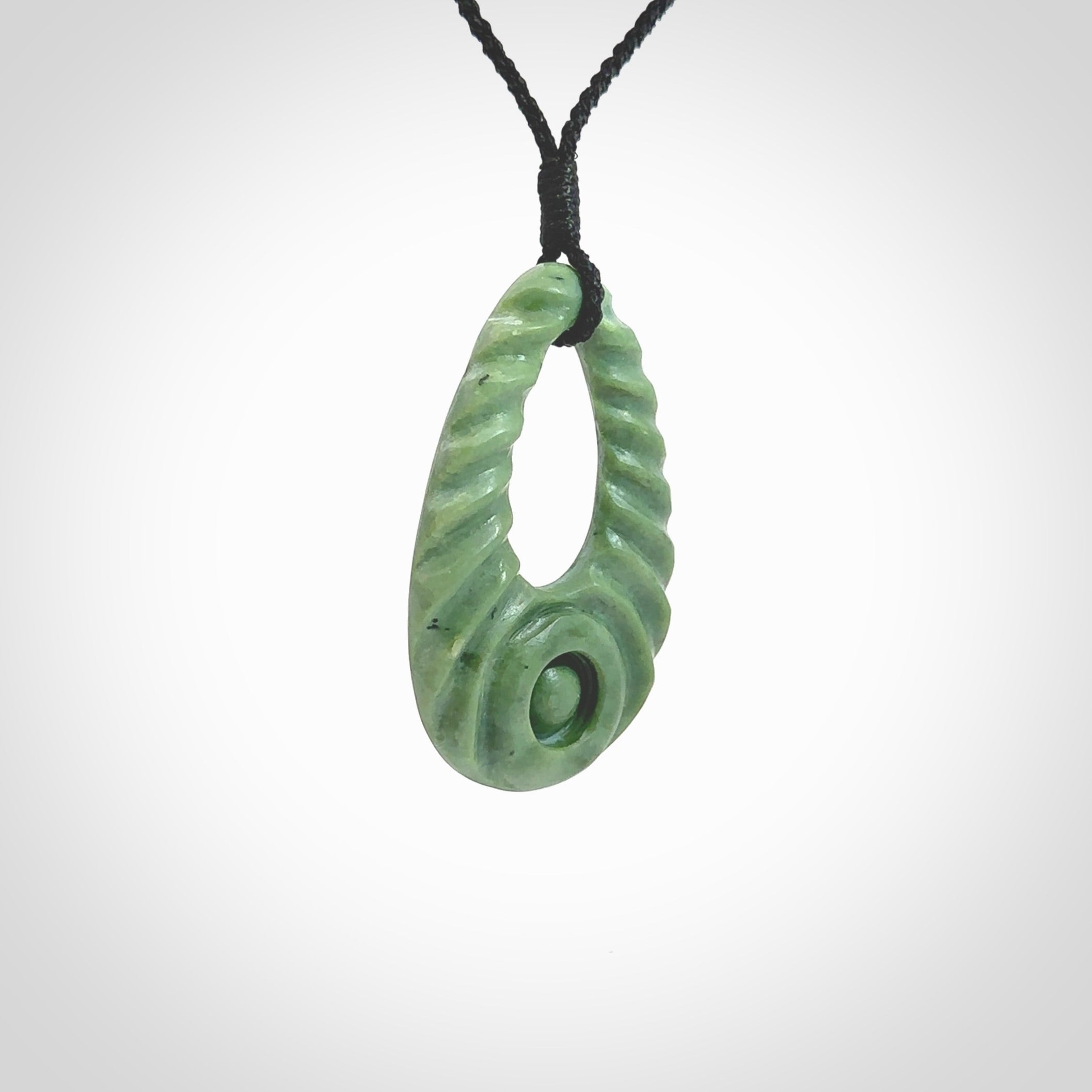 Hand carved New Zealand Jade ripples drop pendant. Made by Ana Krakosky for NZ Pacific in New Zealand Pounamu, jade. A beautiful light green jade ripples drop necklace with black adjustable cord.