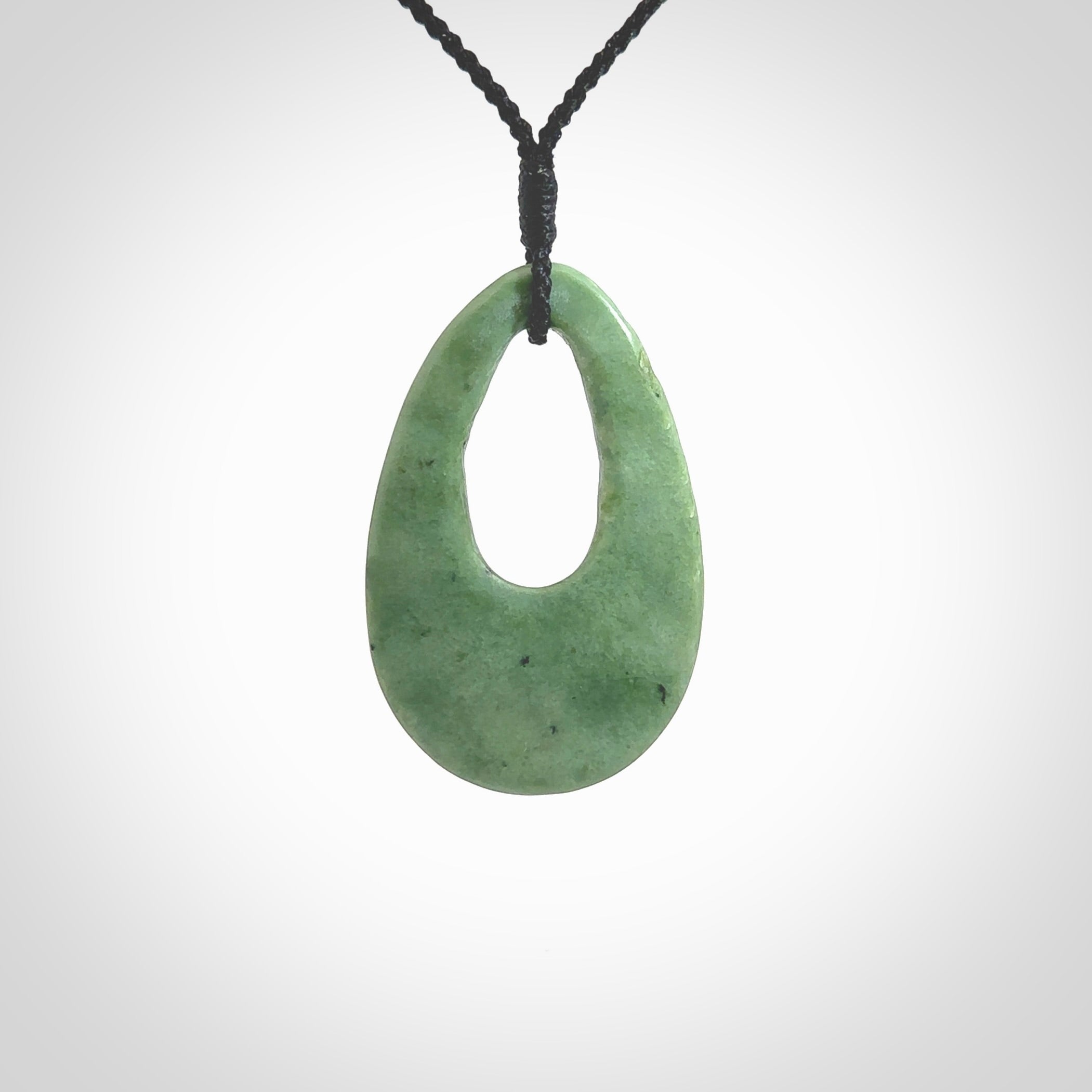 Hand carved New Zealand Jade ripples drop pendant. Made by Ana Krakosky for NZ Pacific in New Zealand Pounamu, jade. A beautiful light green jade ripples drop necklace with black adjustable cord.