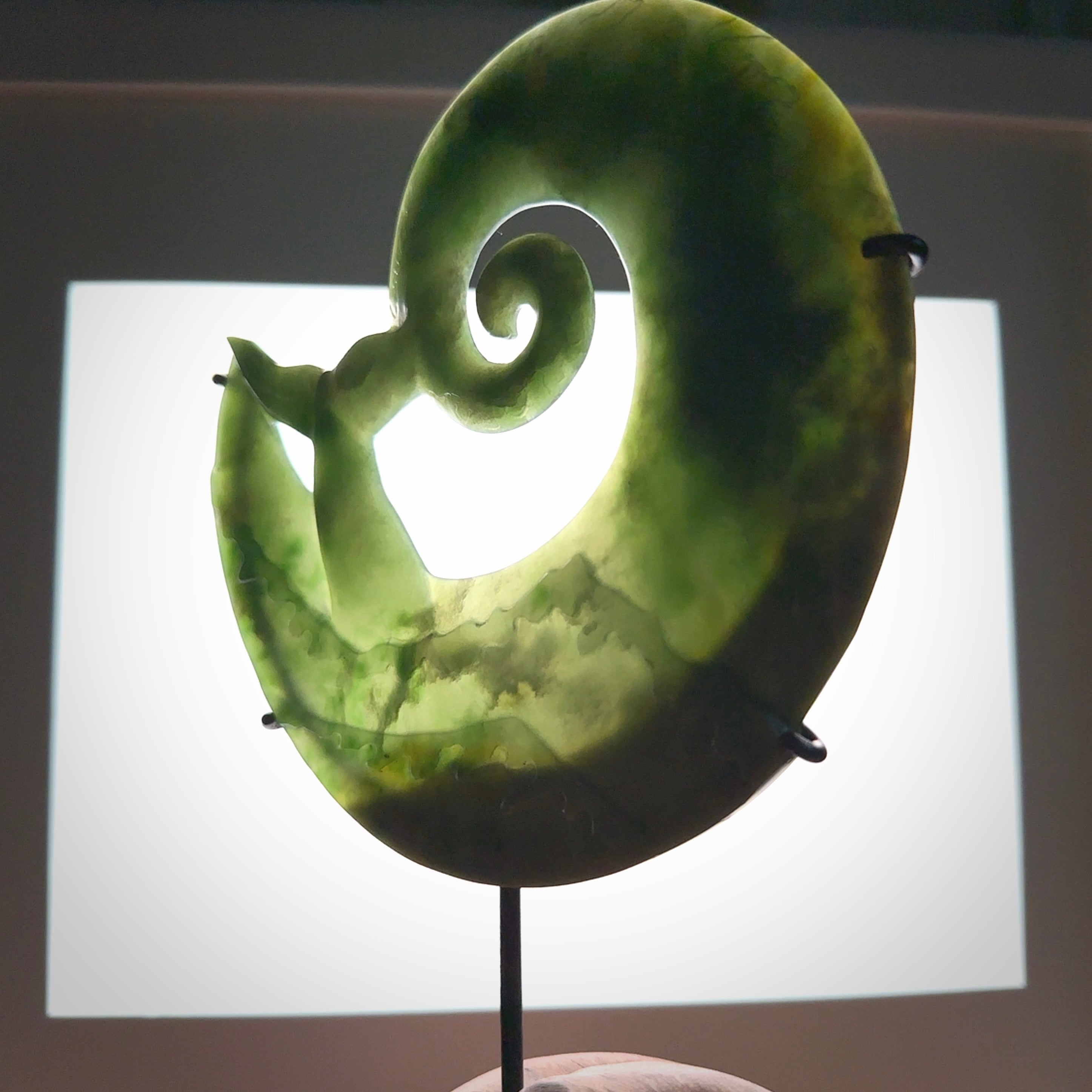 A photo of a New Zealand Jade whale tail in a wave sculpture with Rata Burr stand. This is a statement piece - hand crafted here in New Zealand by Ana Krakosky. Unique Art to display. Gifts for all lovers of hand made sculptures.