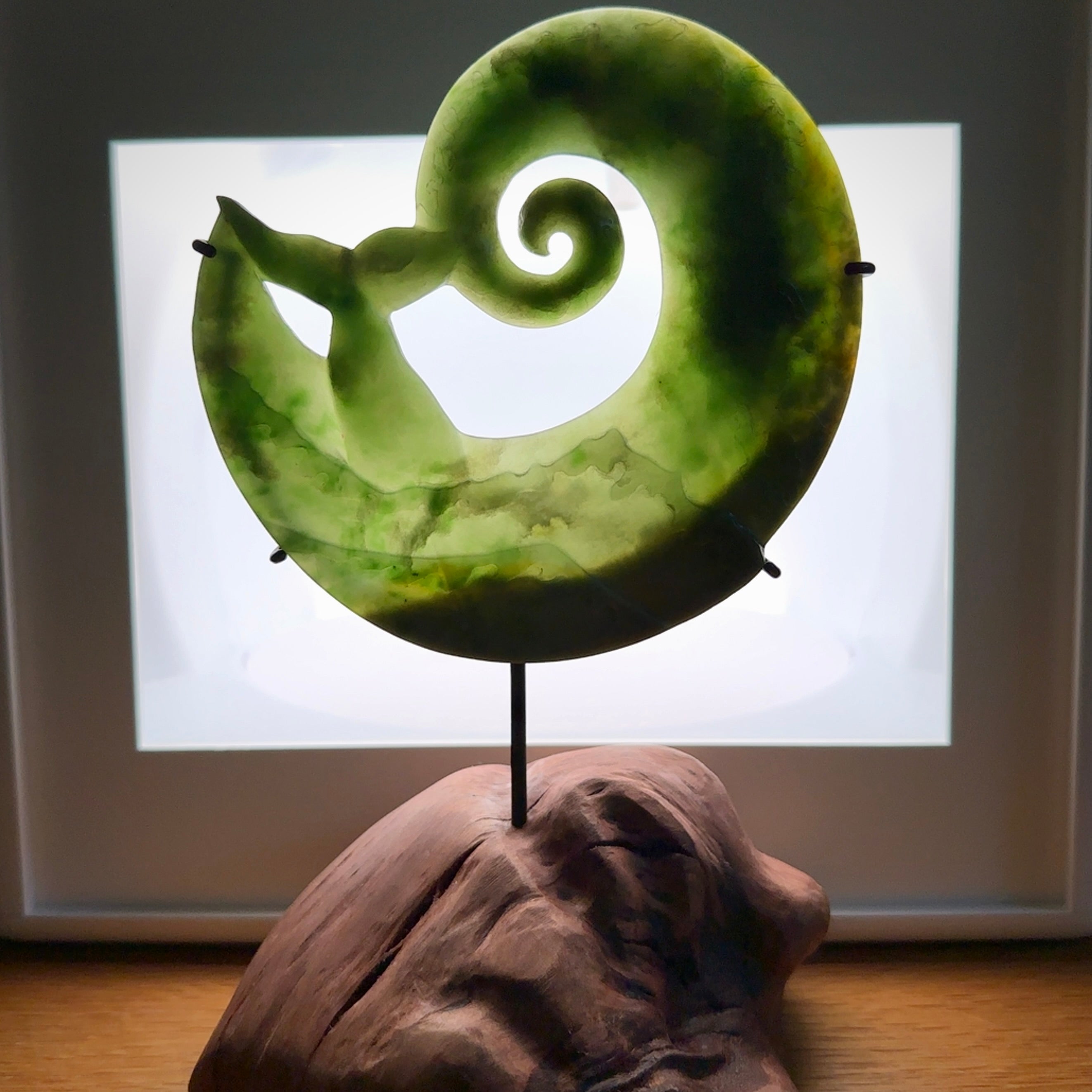 A photo of a New Zealand Jade whale tail in a wave sculpture with Rata Burr stand. This is a statement piece - hand crafted here in New Zealand by Ana Krakosky. Unique Art to display. Gifts for all lovers of hand made sculptures.