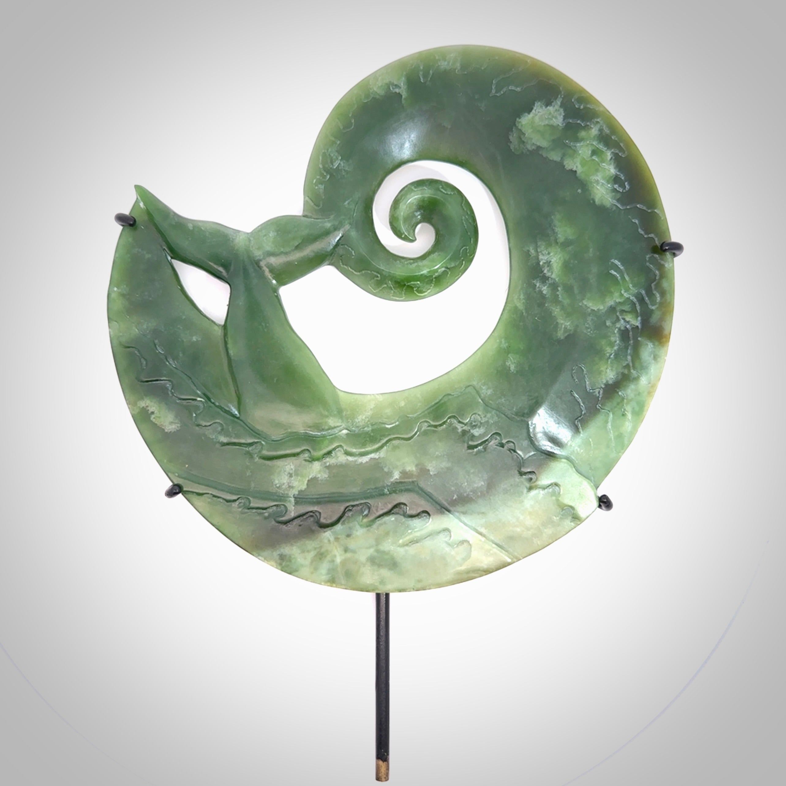 A photo of a New Zealand Jade whale tail in a wave sculpture with Rata Burr stand. This is a statement piece - hand crafted here in New Zealand by Ana Krakosky. Unique Art to display. Gifts for all lovers of hand made sculptures.