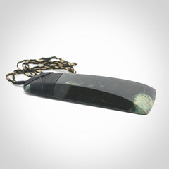 Large Jade Toki pendant. Hand carved from a lovely piece of local New Zealand Jade. The quality of the workmanship and design is outstanding - this is a piece you will want to wear all the time. We have suspended this from an adjustable 3-plait tan/black cord and black binding.