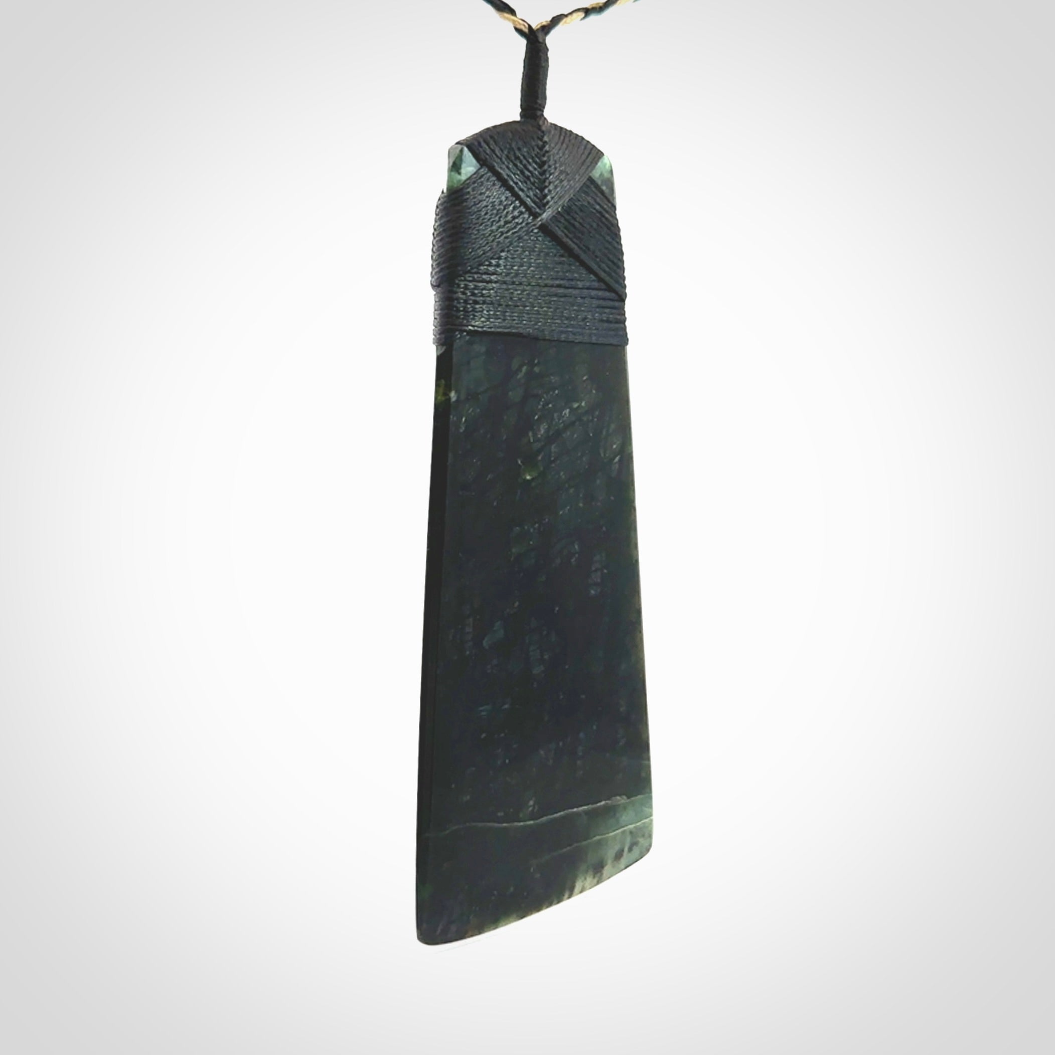 Large Jade Toki pendant. Hand carved from a lovely piece of local New Zealand Jade. The quality of the workmanship and design is outstanding - this is a piece you will want to wear all the time. We have suspended this from an adjustable 3-plait tan/black cord and black binding.