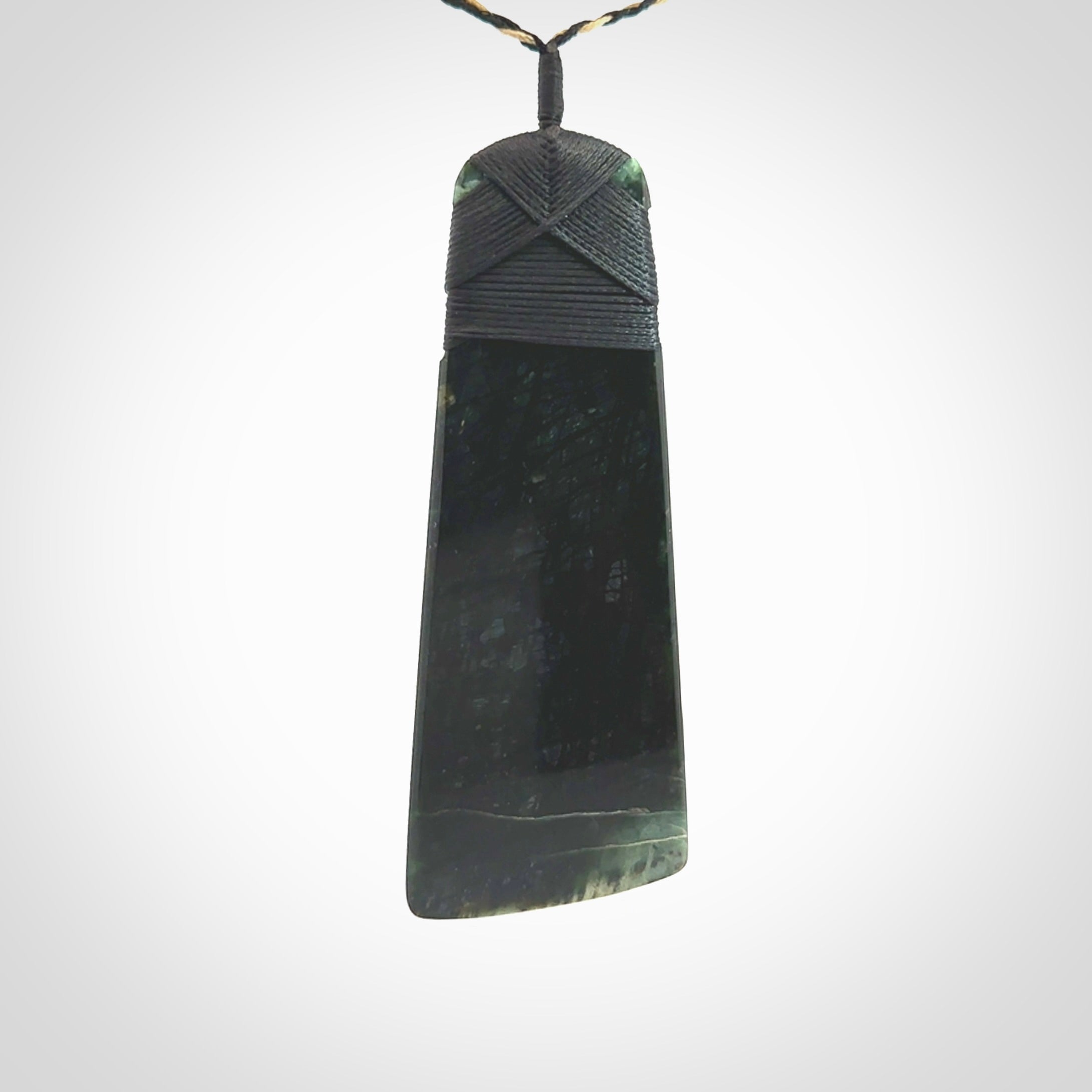 Large Jade Toki pendant. Hand carved from a lovely piece of local New Zealand Jade. The quality of the workmanship and design is outstanding - this is a piece you will want to wear all the time. We have suspended this from an adjustable 3-plait tan/black cord and black binding.