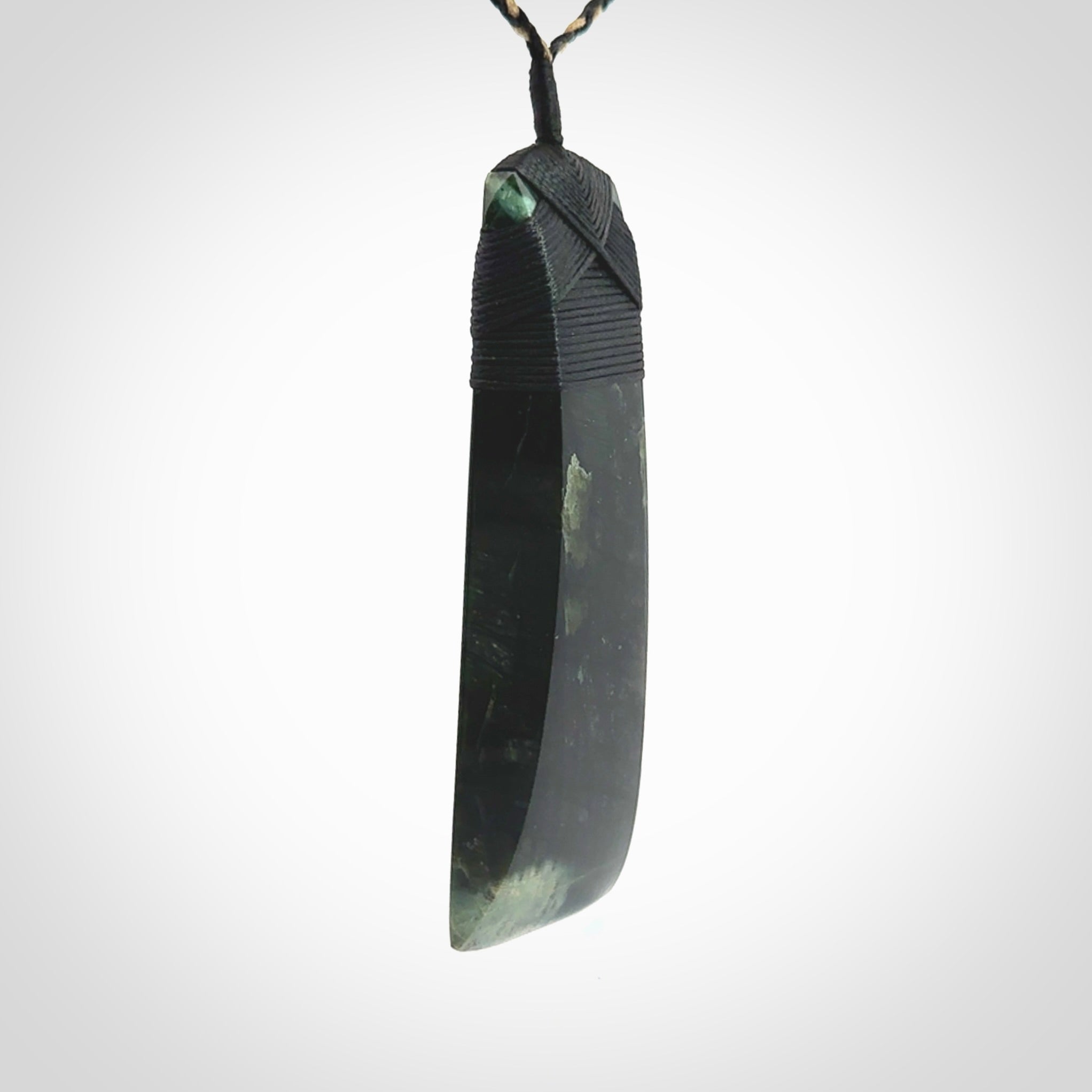 Large Jade Toki pendant. Hand carved from a lovely piece of local New Zealand Jade. The quality of the workmanship and design is outstanding - this is a piece you will want to wear all the time. We have suspended this from an adjustable 3-plait tan/black cord and black binding.