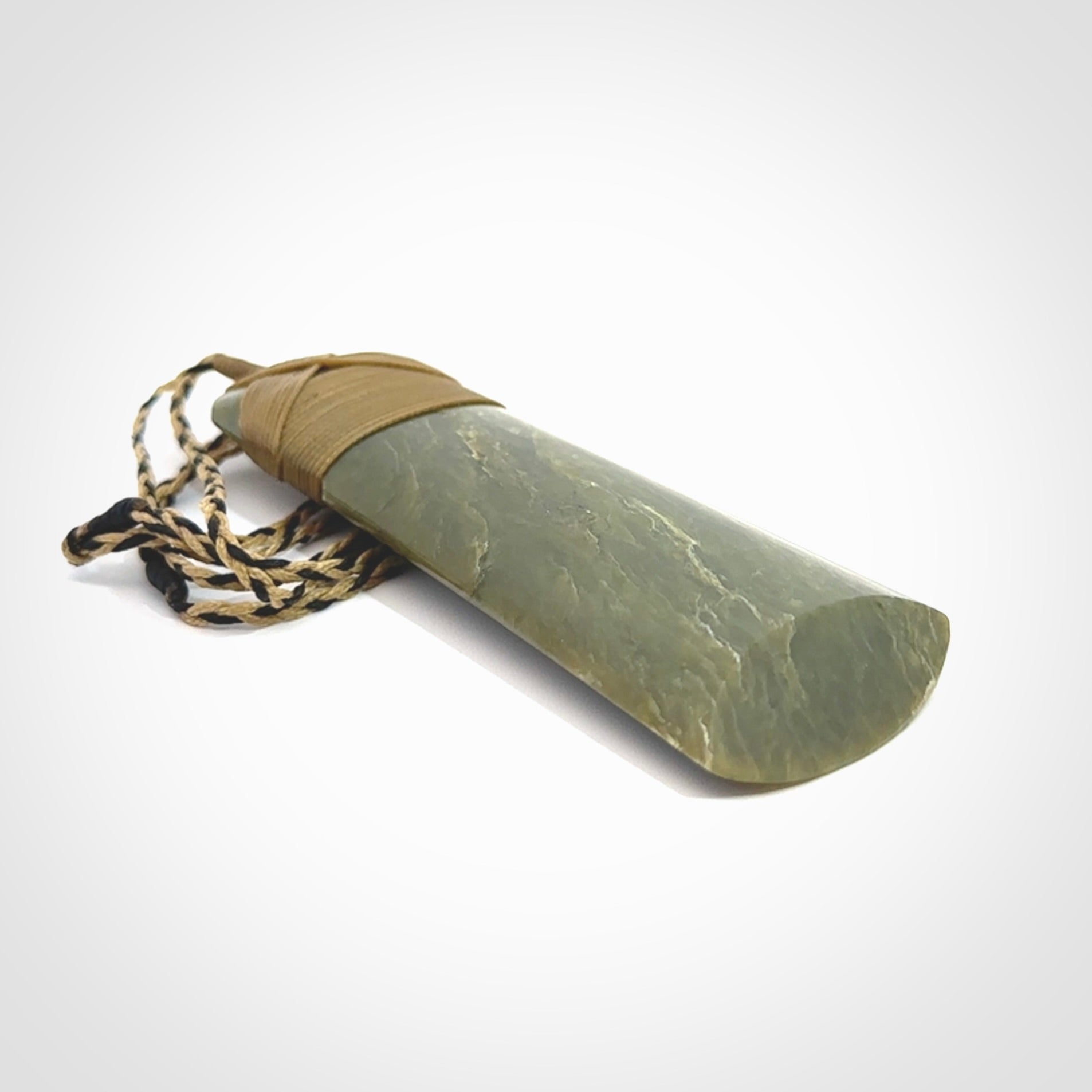 Large Jade Toki pendant. Hand carved from a lovely piece of local New Zealand Jade. The quality of the workmanship and design is outstanding - this is a piece you will want to wear all the time. We have suspended this from an adjustable 3-plait tan/black cord.