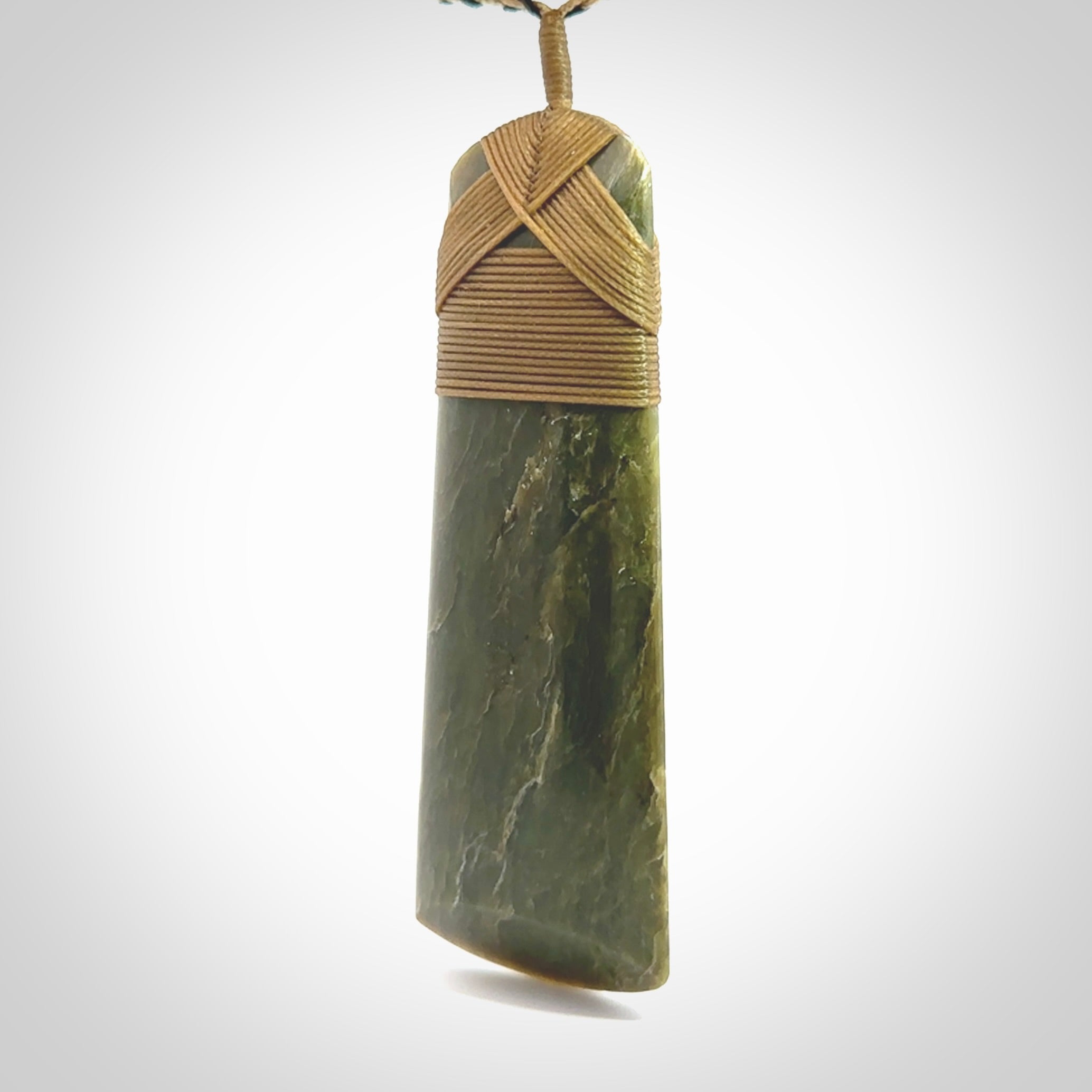 Large Jade Toki pendant. Hand carved from a lovely piece of local New Zealand Jade. The quality of the workmanship and design is outstanding - this is a piece you will want to wear all the time. We have suspended this from an adjustable 3-plait tan/black cord.