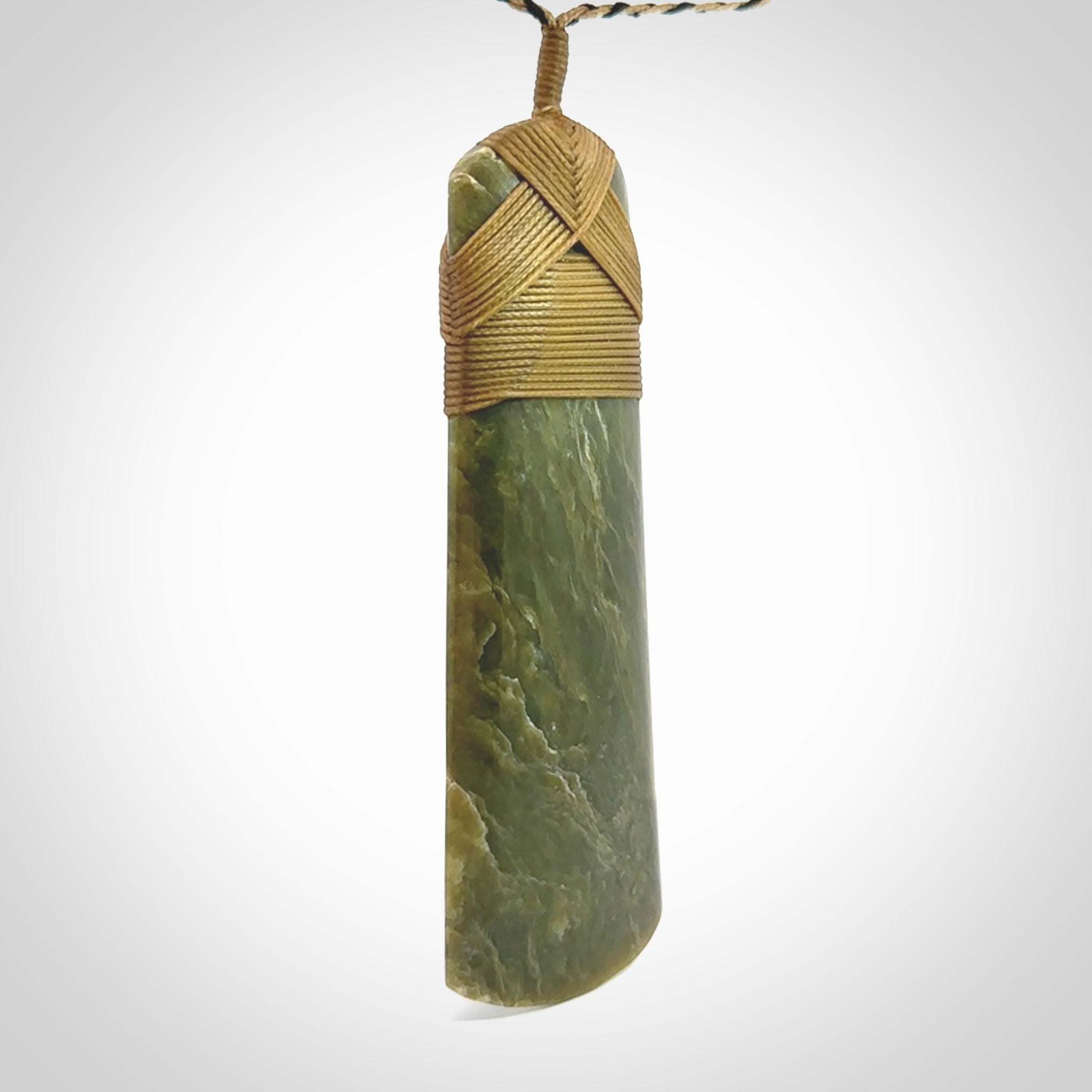 Large Jade Toki pendant. Hand carved from a lovely piece of local New Zealand Jade. The quality of the workmanship and design is outstanding - this is a piece you will want to wear all the time. We have suspended this from an adjustable 3-plait tan/black cord.