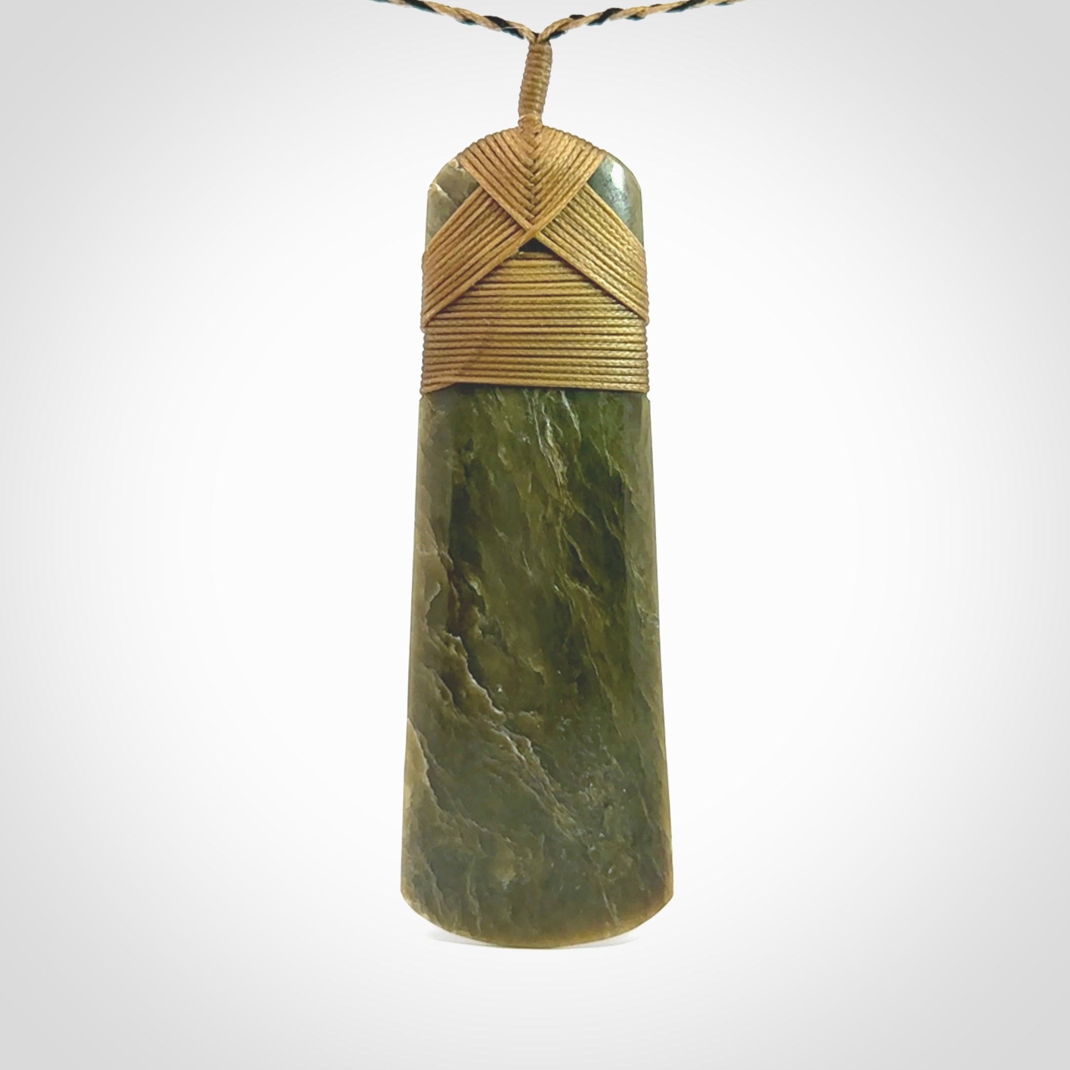 Large Jade Toki pendant. Hand carved from a lovely piece of local New Zealand Jade. The quality of the workmanship and design is outstanding - this is a piece you will want to wear all the time. We have suspended this from an adjustable 3-plait tan/black cord.