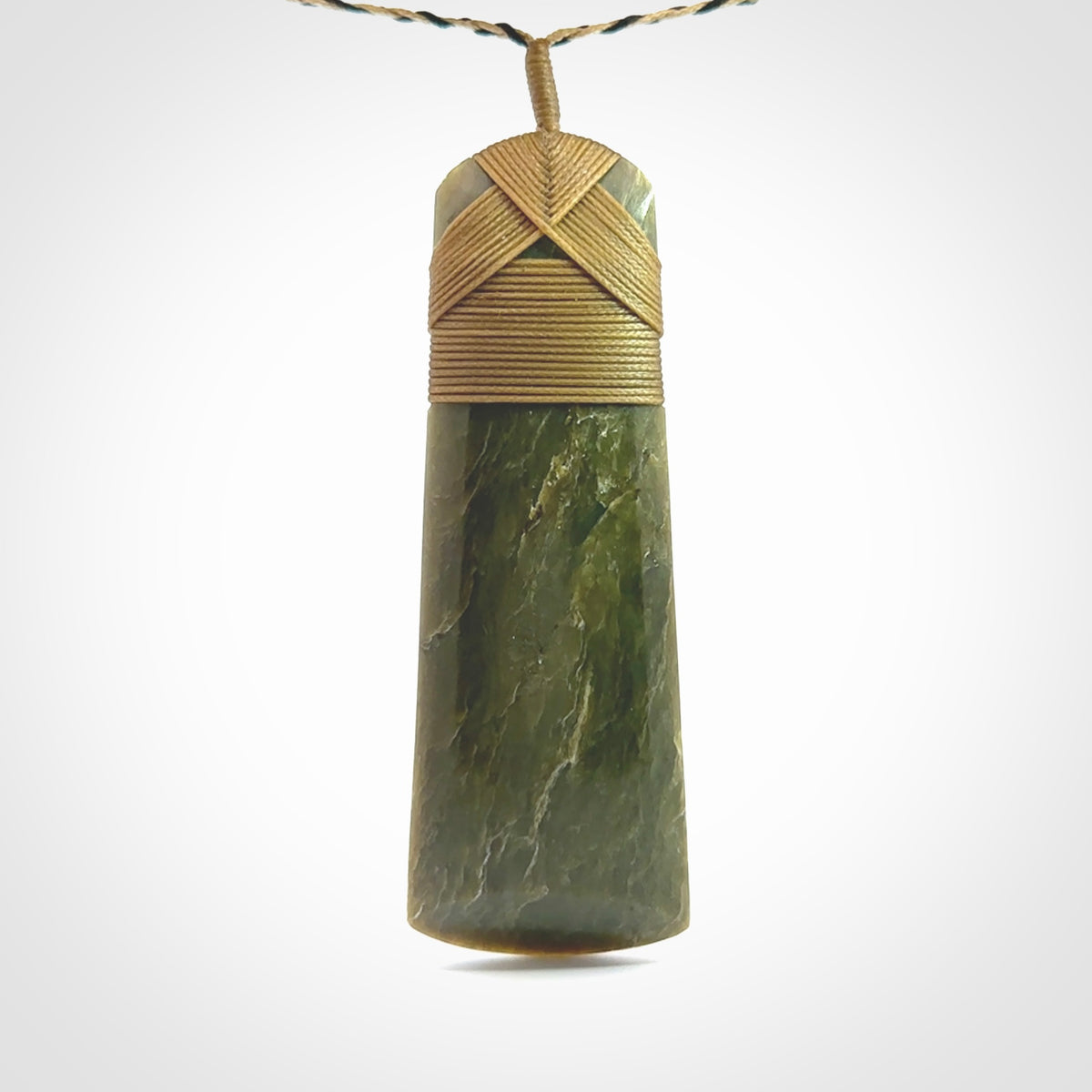 Large Jade Toki pendant. Hand carved from a lovely piece of local New Zealand Jade. The quality of the workmanship and design is outstanding - this is a piece you will want to wear all the time. We have suspended this from an adjustable 3-plait tan/black cord.