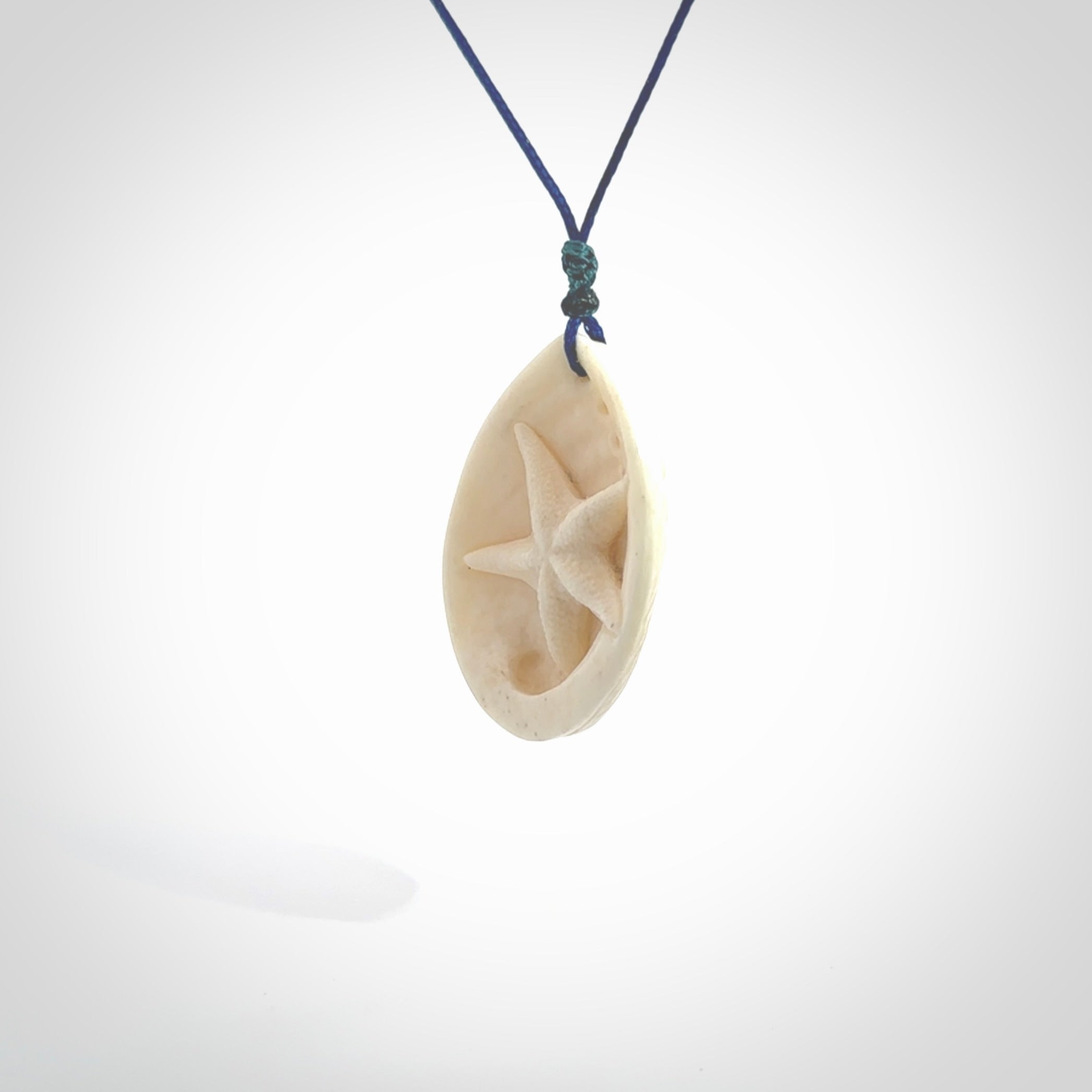 Hand carved bone paua shell with starfish inside pendant. Made from Bone in New Zealand. Unique Pāua Shell necklace hand made from bone with starfish carving inside the shell. Made by master bone carver Fumio Noguchi. Spectacular collectable work of art, made to wear. One only pendant, delivered to you with express courier on a blue adjustable cord.