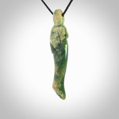 Hand carved New Zealand Flower Jade woman drop pendant. Made by Ana Krakosky for NZ Pacific in New Zealand Pounamu, jade. A beautiful green and light orange jade figure of a woman, drop necklace with black adjustable cord.