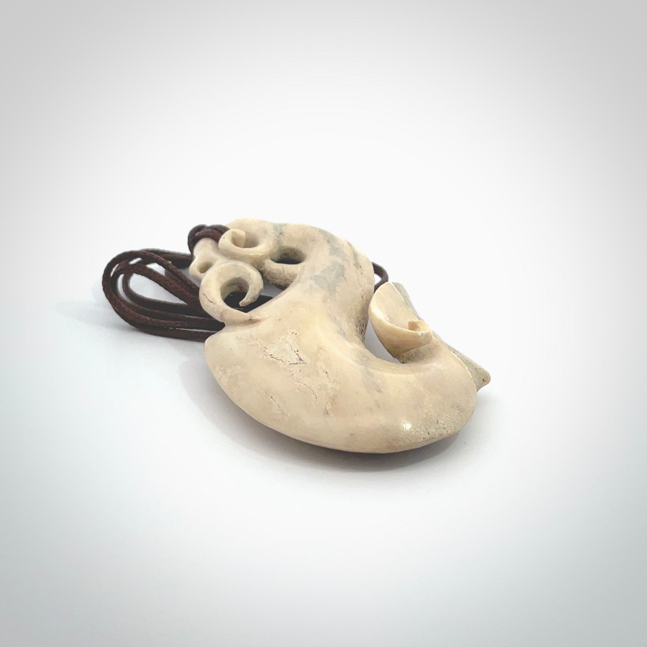 Hand made deer antler manaia pendant. Hand carved by NZ Pacific. Manaia carved from deer antler pendant for sale online. Delivered to you on an adjustable chocolate brown cord and packaged in a woven kete pouch.