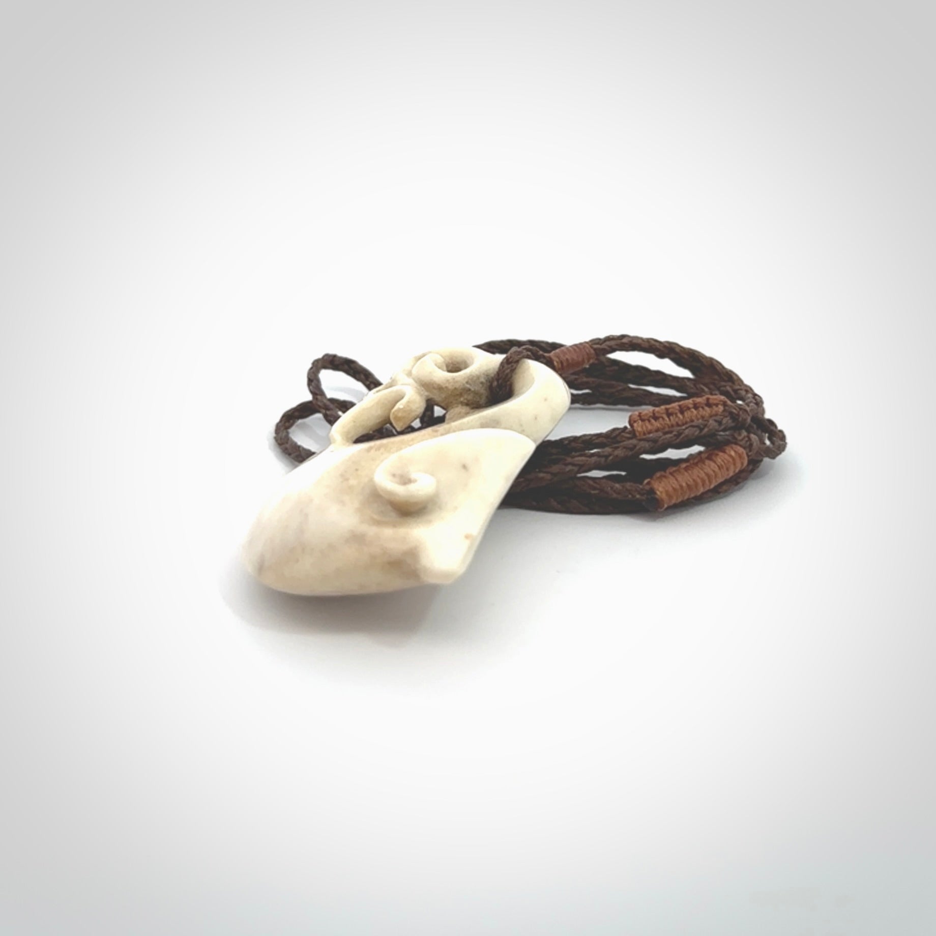 Hand made deer antler manaia pendant. Hand carved by NZ Pacific. Manaia carved from deer antler pendant for sale online. Delivered to you on an adjustable brown cord and packaged in a woven kete pouch.