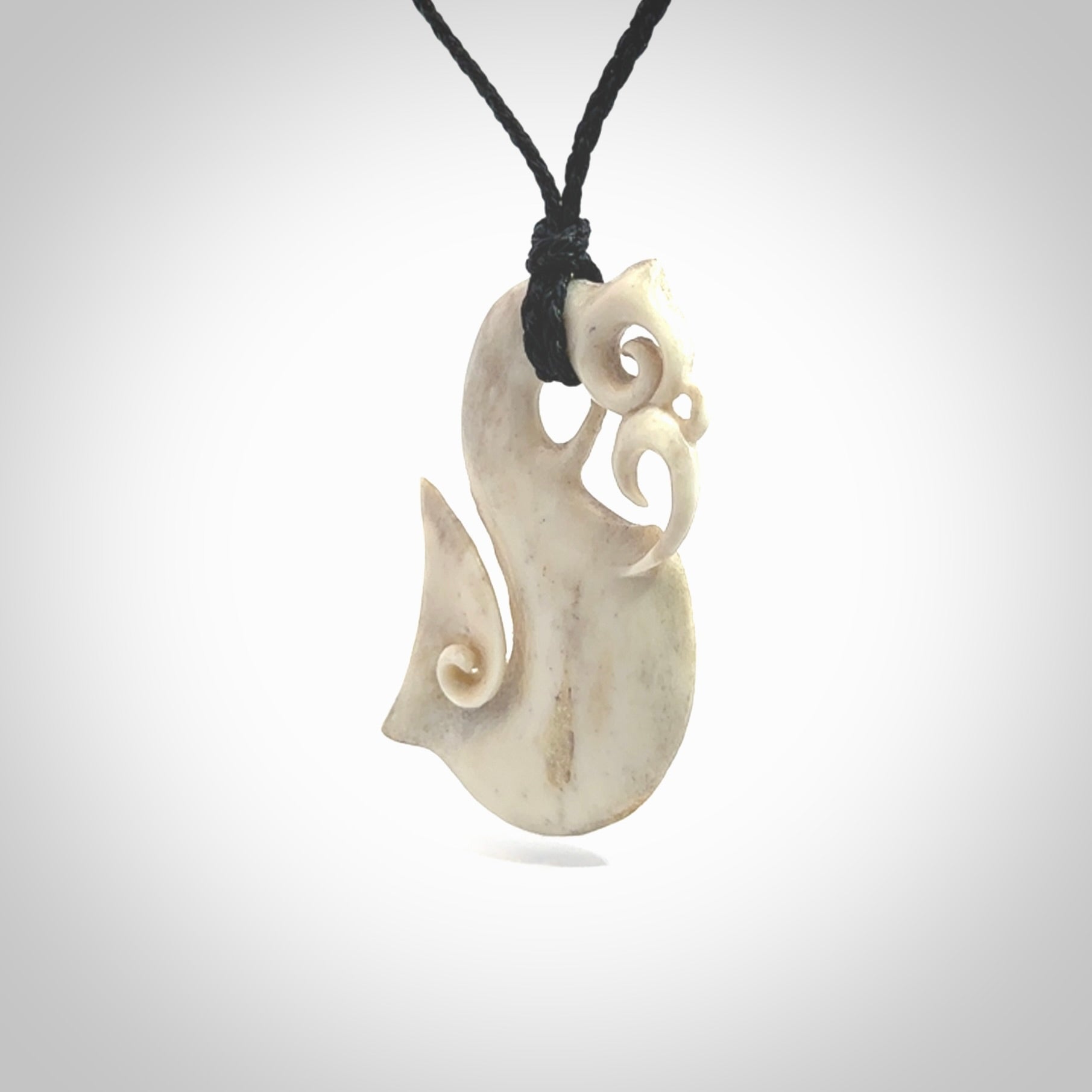 Hand made deer antler manaia pendant. Hand carved by NZ Pacific. Manaia carved from deer antler pendant for sale online. Delivered to you on an adjustable black cord and packaged in a woven kete pouch.