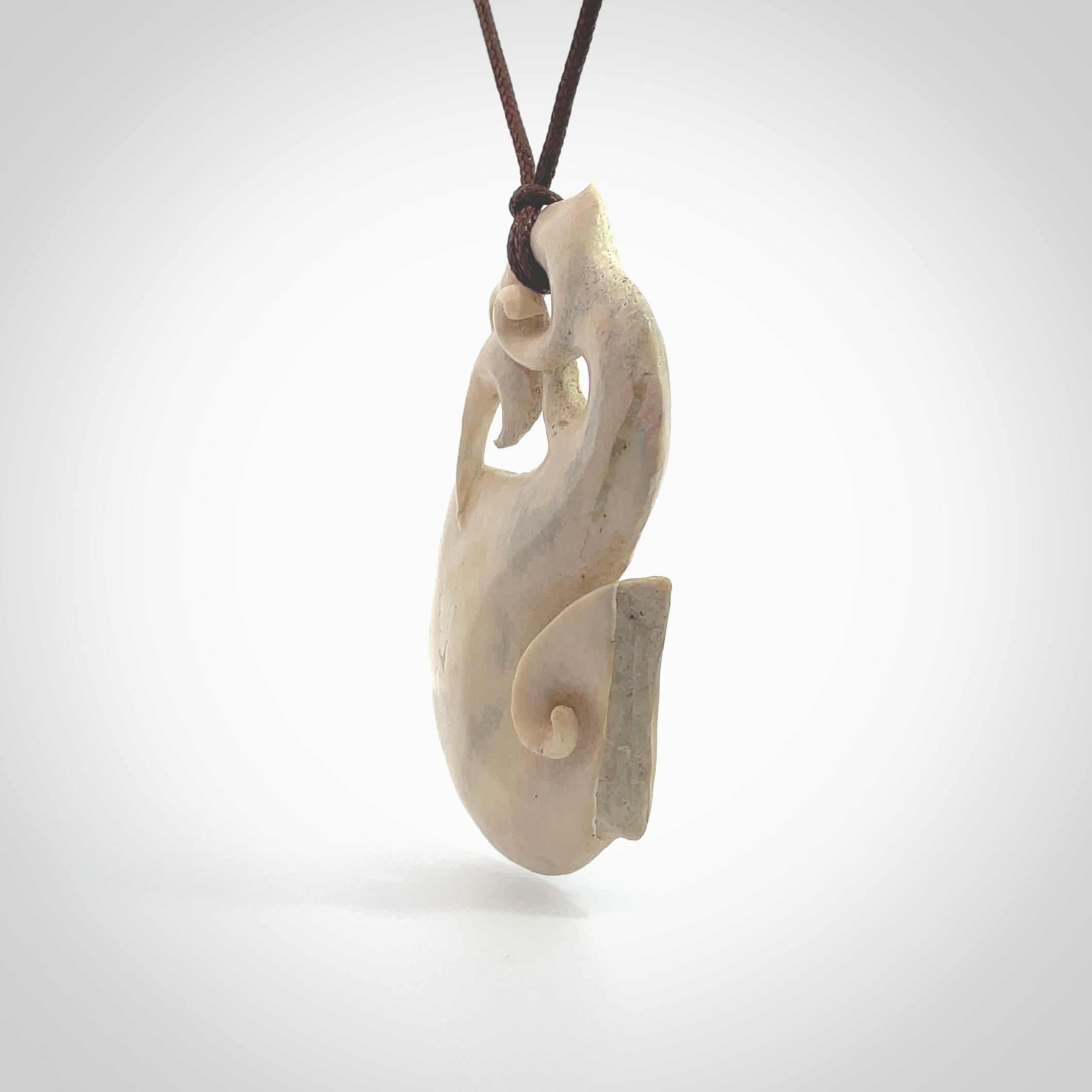 Hand made deer antler manaia pendant. Hand carved by NZ Pacific. Manaia carved from deer antler pendant for sale online. Delivered to you on an adjustable chocolate brown cord and packaged in a woven kete pouch.