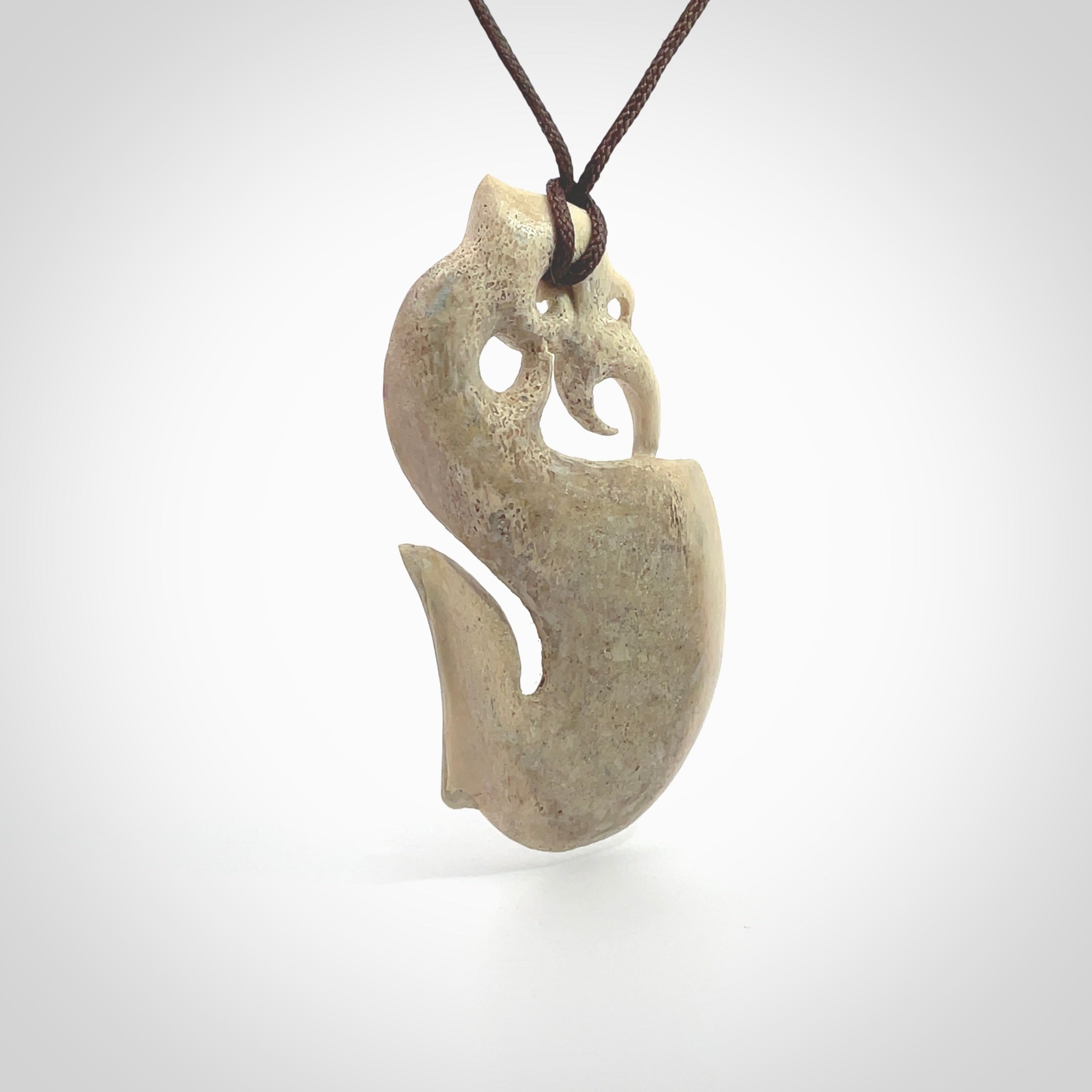 Hand made deer antler manaia pendant. Hand carved by NZ Pacific. Manaia carved from deer antler pendant for sale online. Delivered to you on an adjustable chocolate brown cord and packaged in a woven kete pouch.