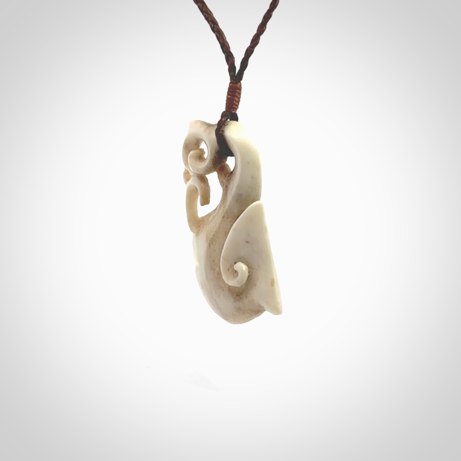 Hand made deer antler manaia pendant. Hand carved by NZ Pacific. Manaia carved from deer antler pendant for sale online. Delivered to you on an adjustable brown cord and packaged in a woven kete pouch.