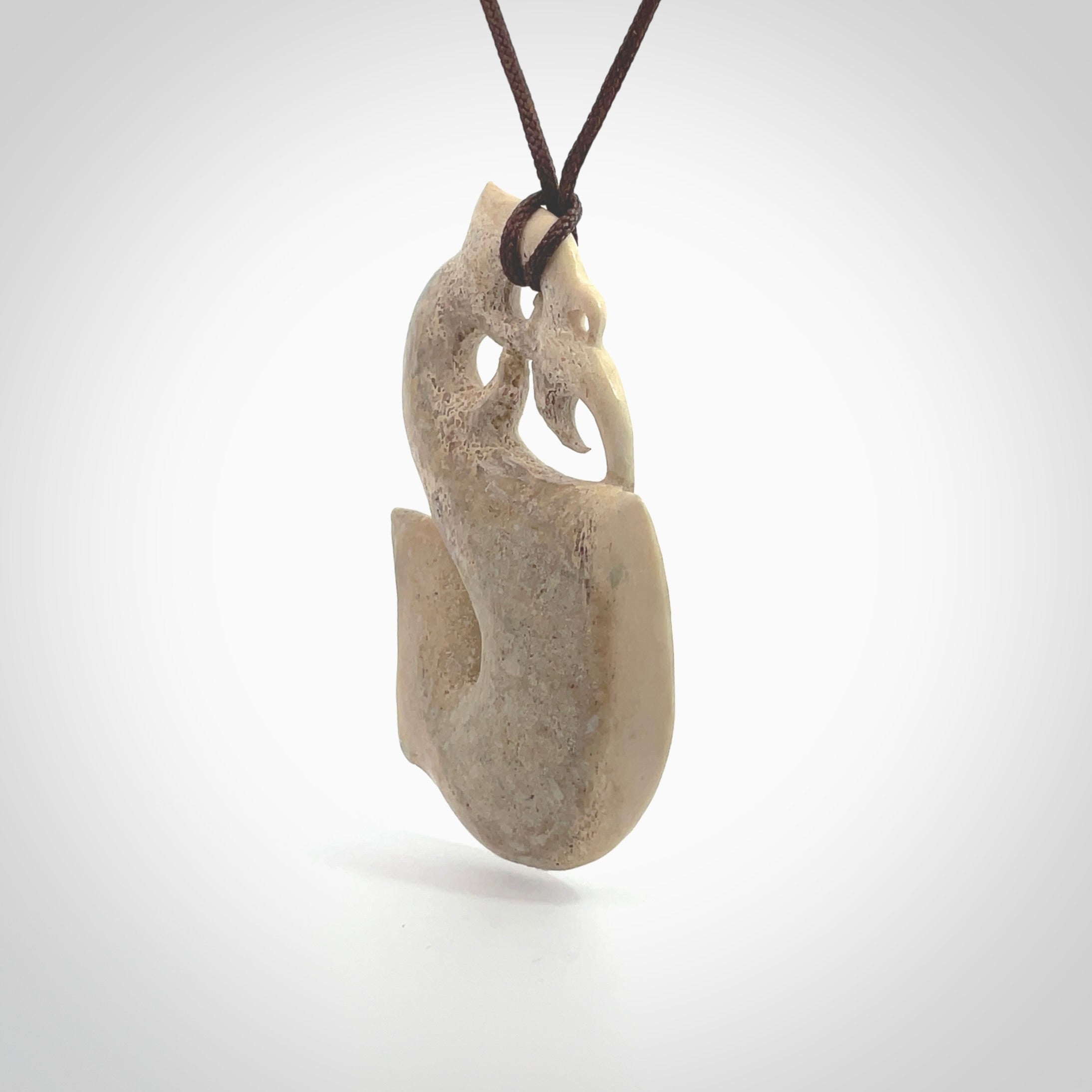 Hand made deer antler manaia pendant. Hand carved by NZ Pacific. Manaia carved from deer antler pendant for sale online. Delivered to you on an adjustable chocolate brown cord and packaged in a woven kete pouch.