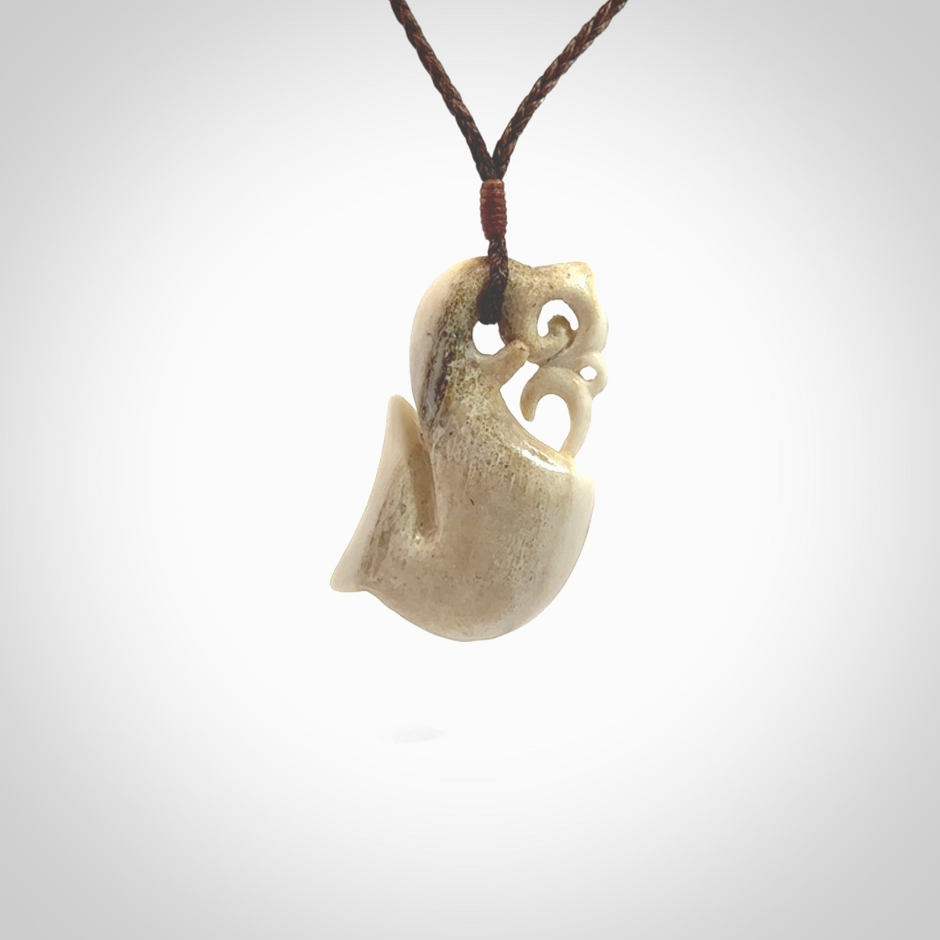 Hand made deer antler manaia pendant. Hand carved by NZ Pacific. Manaia carved from deer antler pendant for sale online. Delivered to you on an adjustable brown cord and packaged in a woven kete pouch.