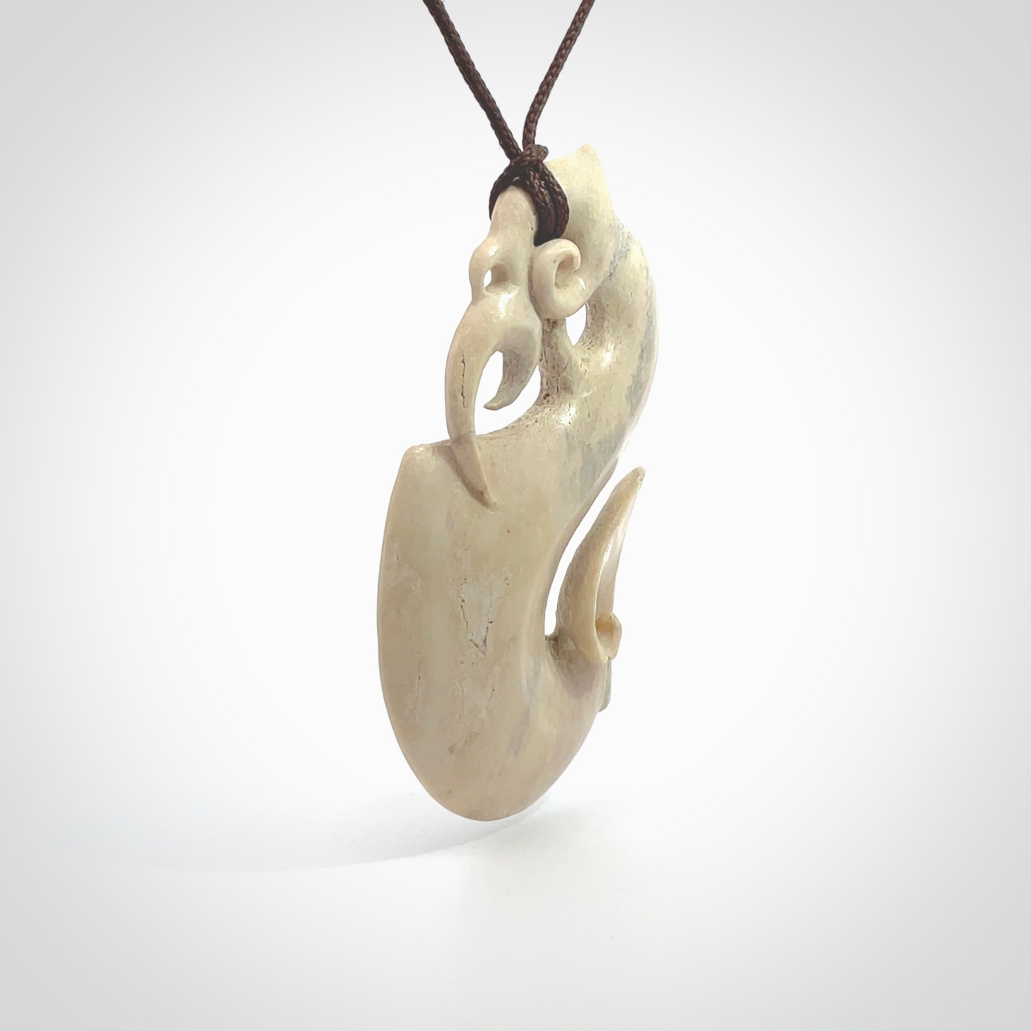 Hand made deer antler manaia pendant. Hand carved by NZ Pacific. Manaia carved from deer antler pendant for sale online. Delivered to you on an adjustable chocolate brown cord and packaged in a woven kete pouch.