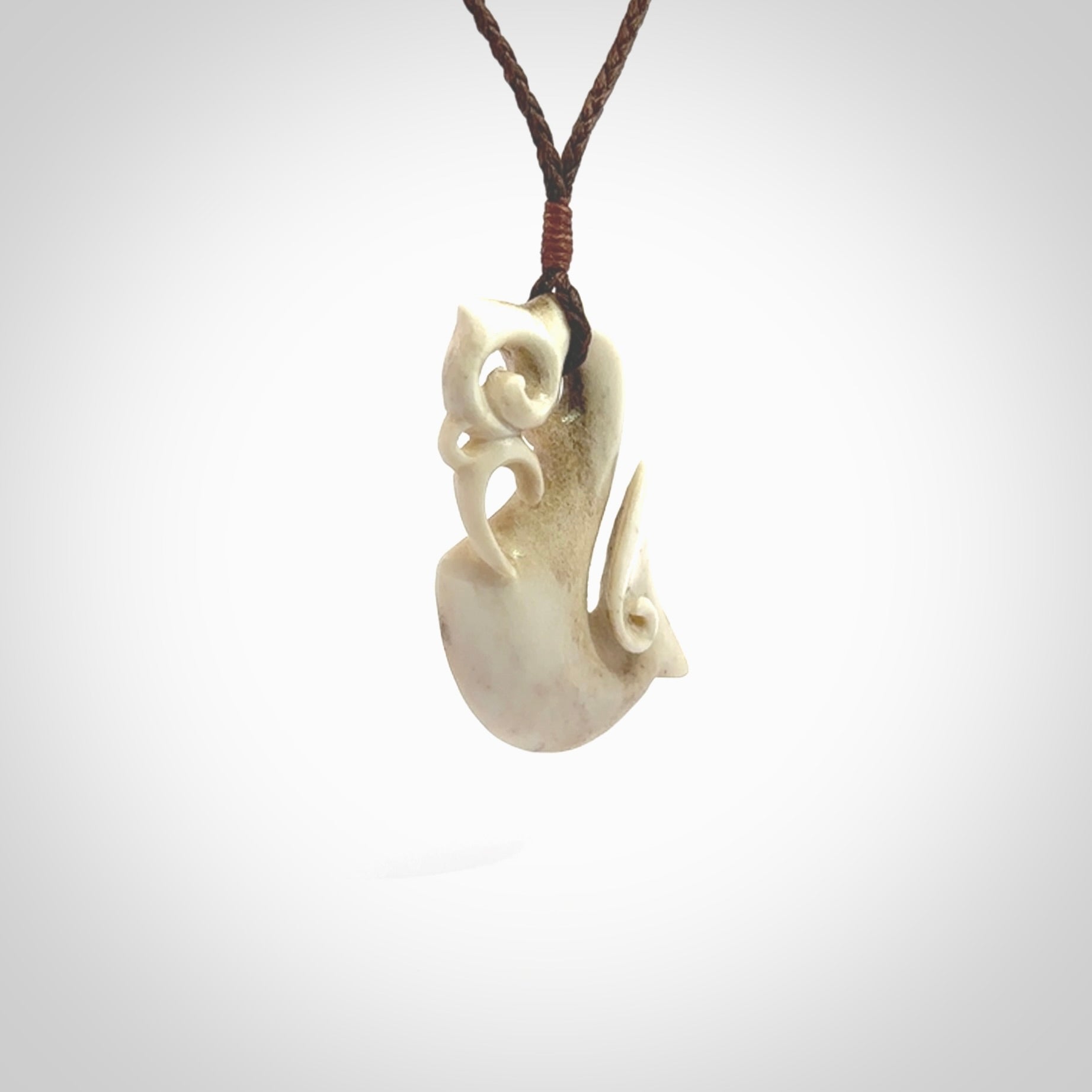 Hand made deer antler manaia pendant. Hand carved by NZ Pacific. Manaia carved from deer antler pendant for sale online. Delivered to you on an adjustable brown cord and packaged in a woven kete pouch.