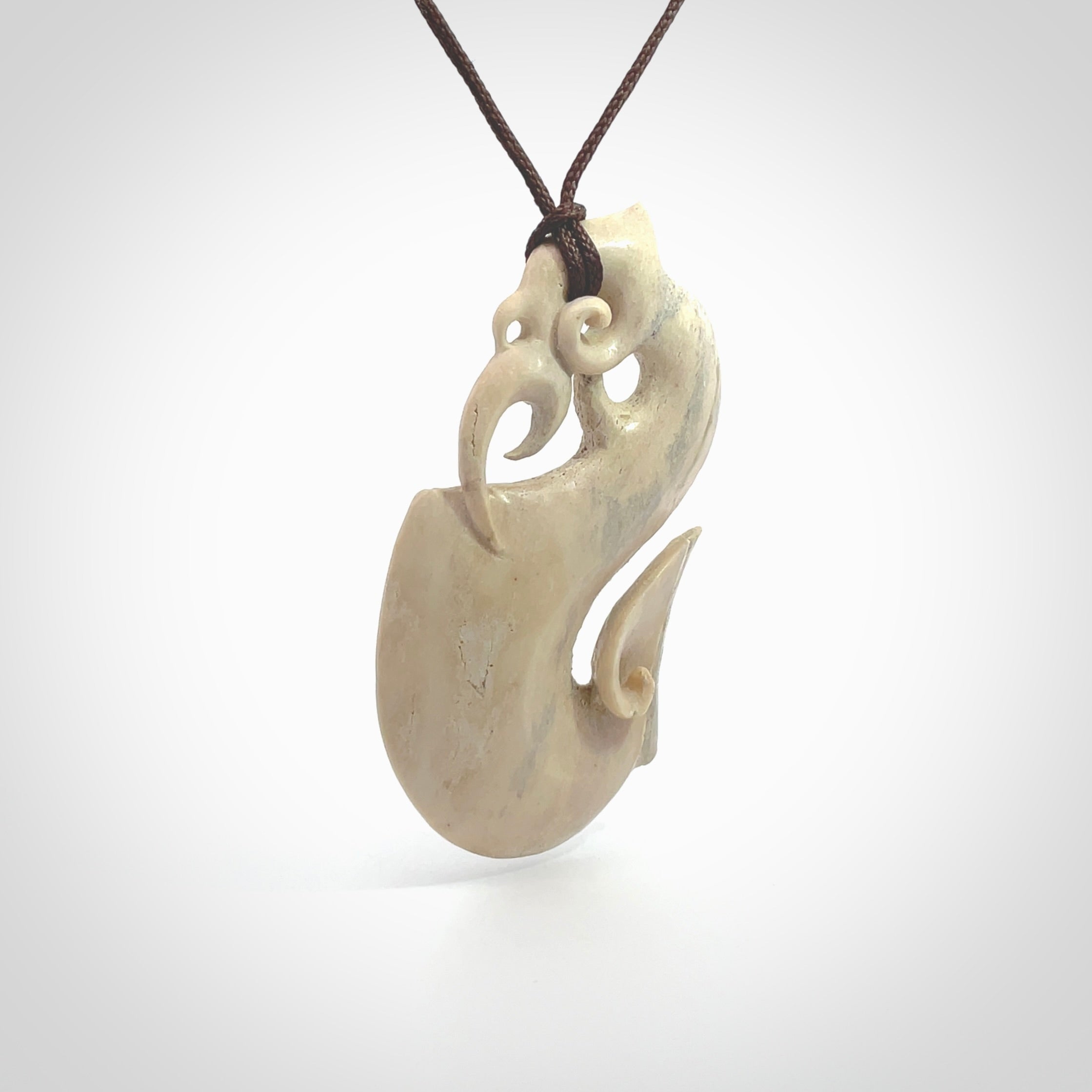 Hand made deer antler manaia pendant. Hand carved by NZ Pacific. Manaia carved from deer antler pendant for sale online. Delivered to you on an adjustable chocolate brown cord and packaged in a woven kete pouch.