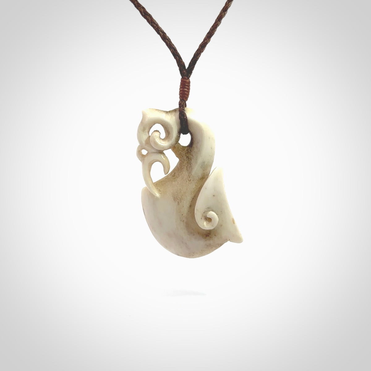 Hand made deer antler manaia pendant. Hand carved by NZ Pacific. Manaia carved from deer antler pendant for sale online. Delivered to you on an adjustable brown cord and packaged in a woven kete pouch.