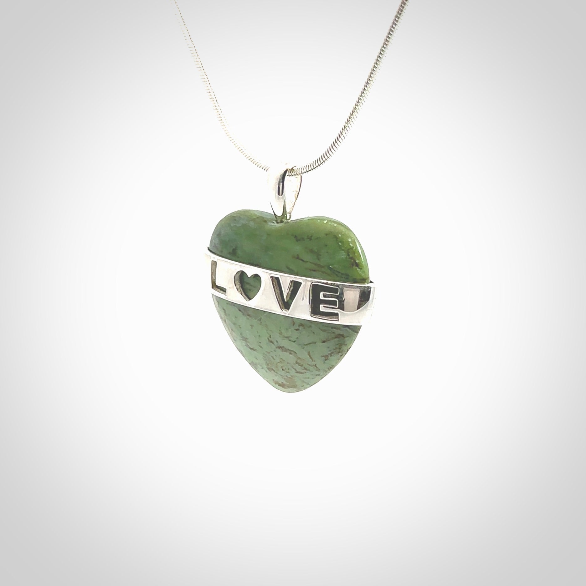 Hand crafted New Zealand jade love heart necklace. This piece has  a sterling silver love written across its' body. This necklace is provided with a sterling silver chain.