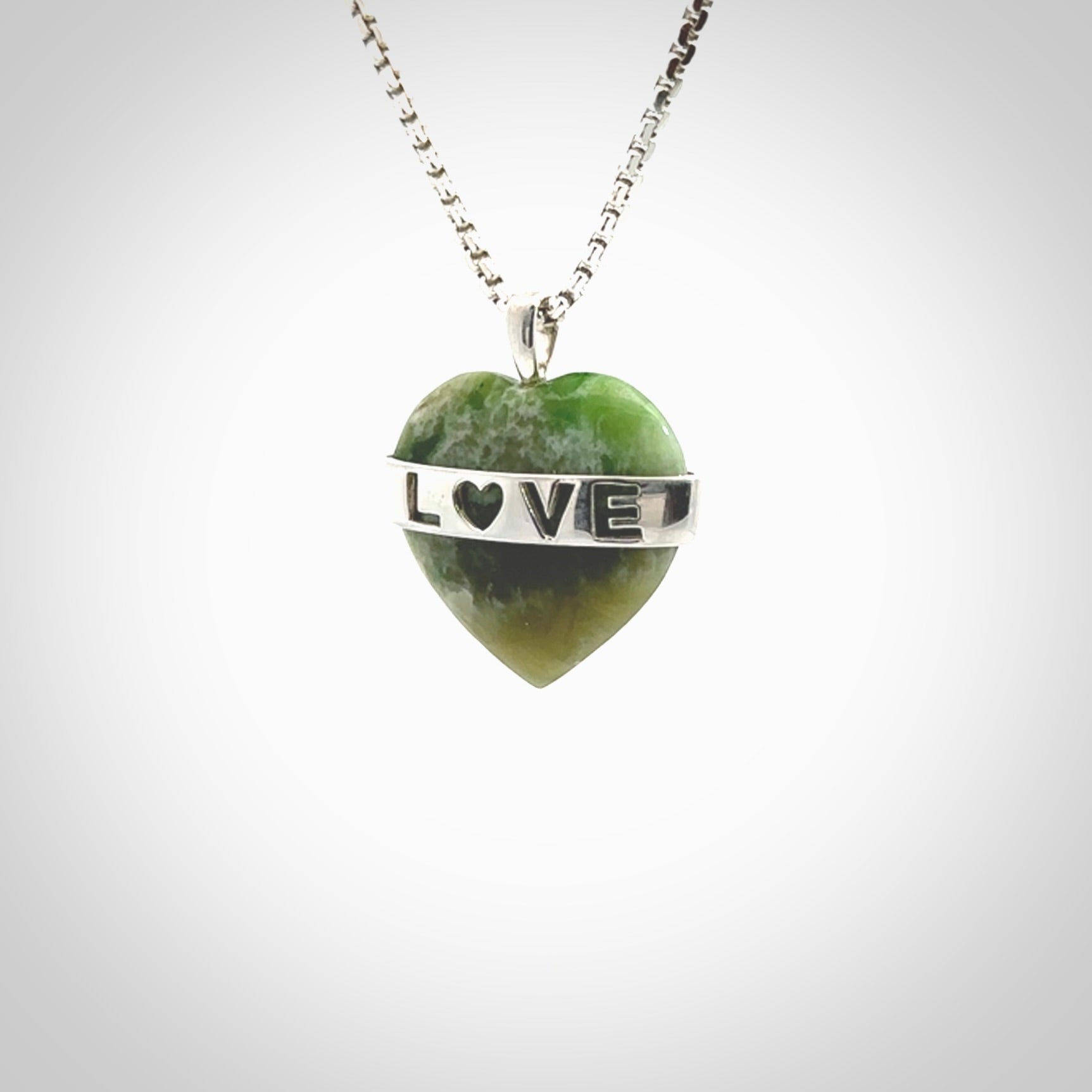 Hand crafted New Zealand jade love heart necklace. This piece has  a sterling silver love written across its' body. This necklace is provided with a sterling silver chain.