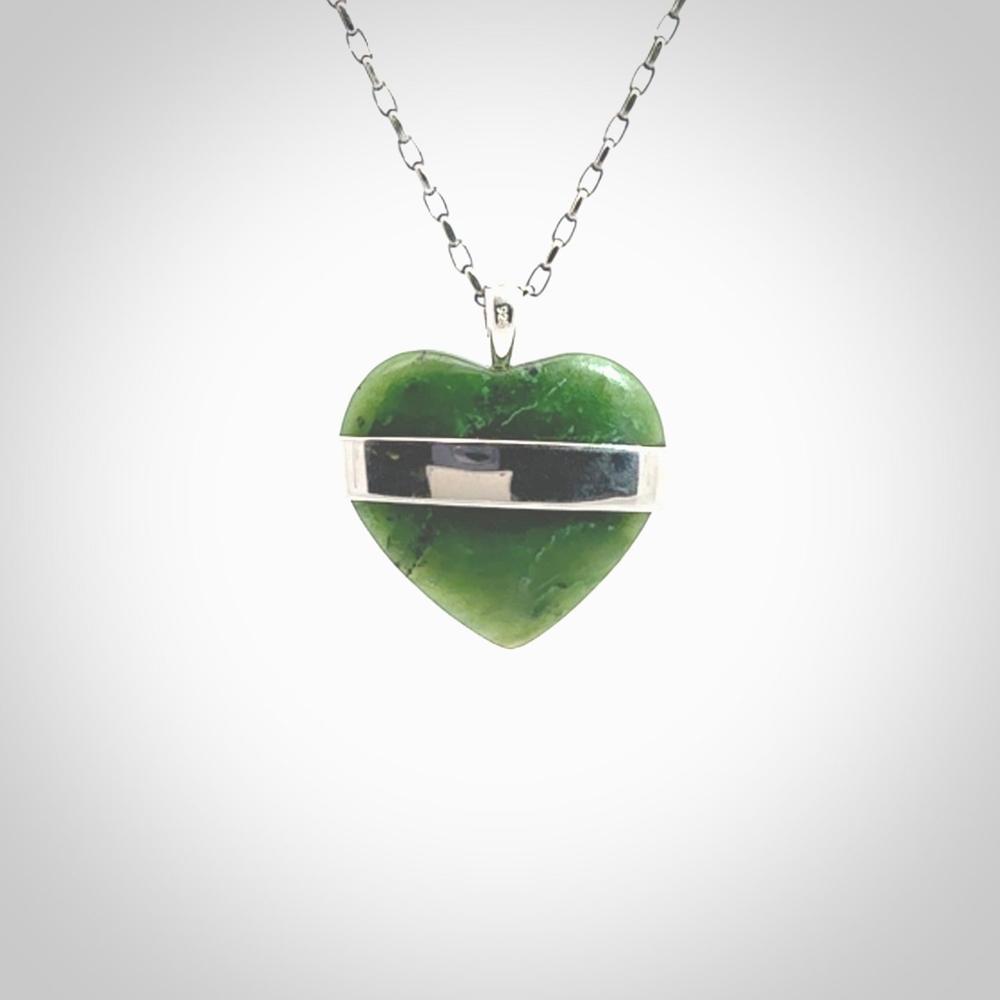 Hand crafted New Zealand jade love heart necklace. This piece has  a sterling silver love written across its' body. This necklace is provided with a sterling silver chain.