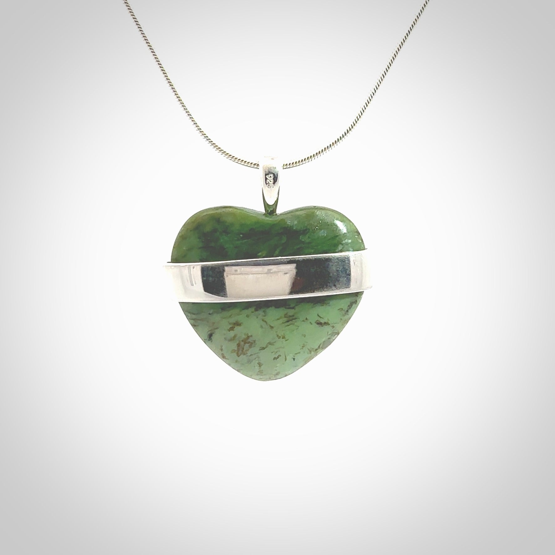 Hand crafted New Zealand jade love heart necklace. This piece has  a sterling silver love written across its' body. This necklace is provided with a sterling silver chain.