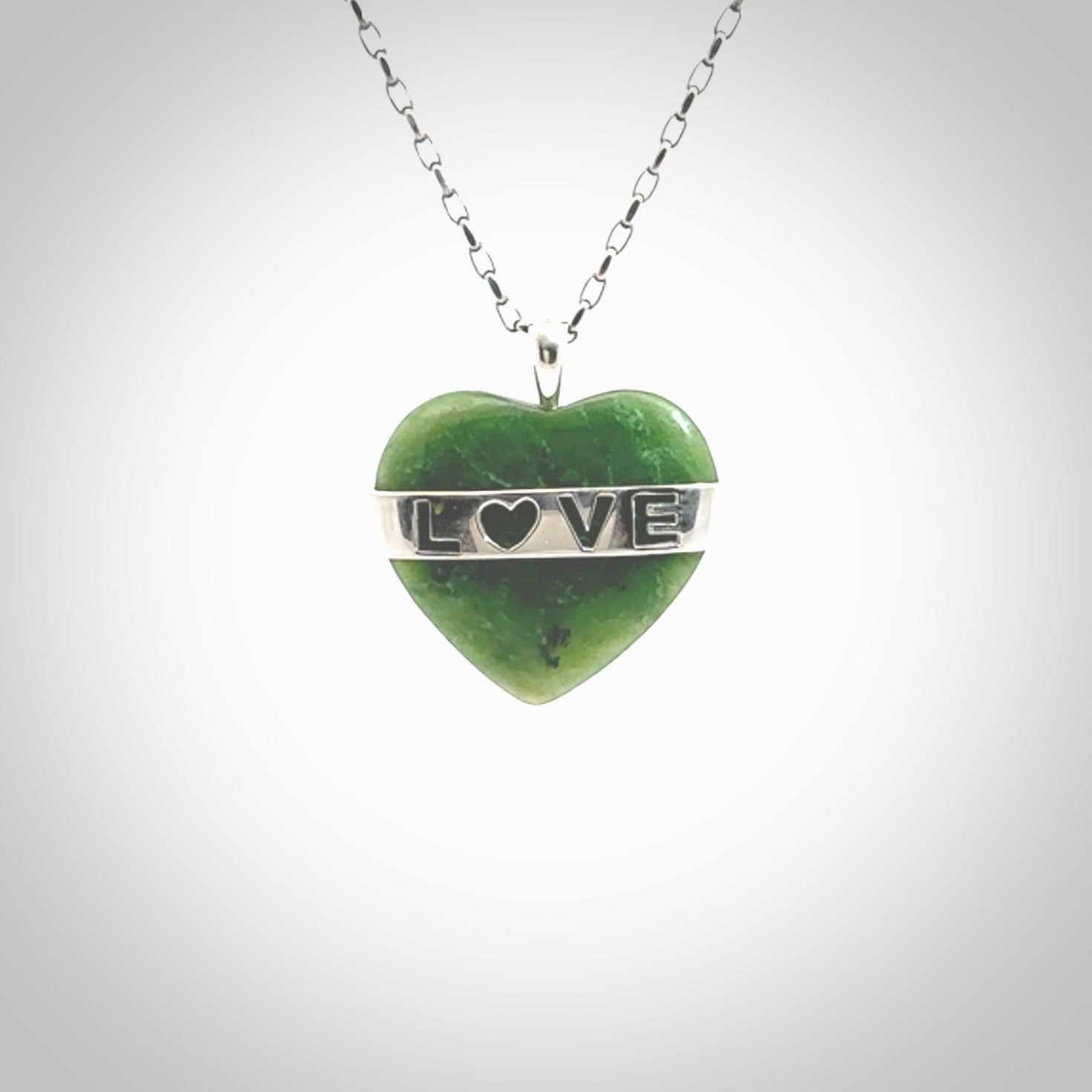 Hand crafted New Zealand jade love heart necklace. This piece has  a sterling silver love written across its' body. This necklace is provided with a sterling silver chain.