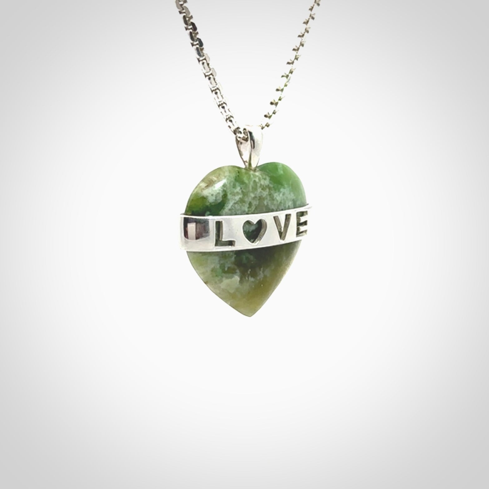 Hand crafted New Zealand jade love heart necklace. This piece has  a sterling silver love written across its' body. This necklace is provided with a sterling silver chain.