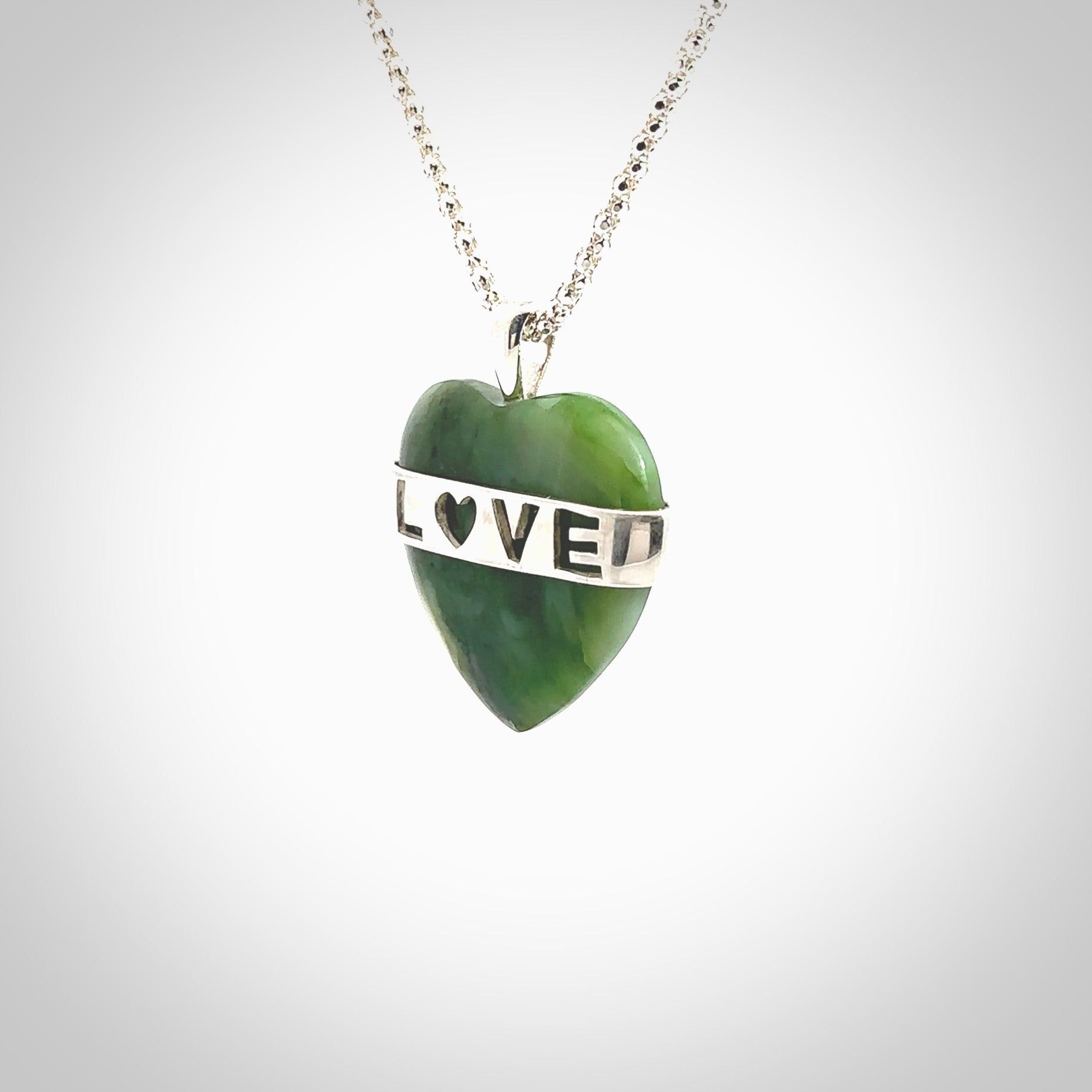 Hand crafted New Zealand jade love heart necklace. This piece has  a sterling silver love written across its' body. This necklace is provided with a sterling silver chain.