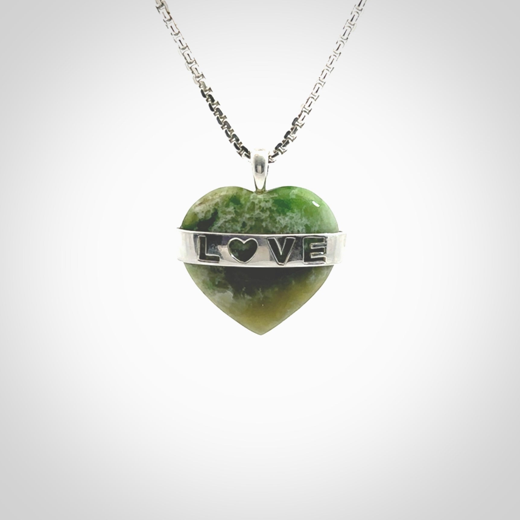 Hand crafted New Zealand jade love heart necklace. This piece has  a sterling silver love written across its' body. This necklace is provided with a sterling silver chain.